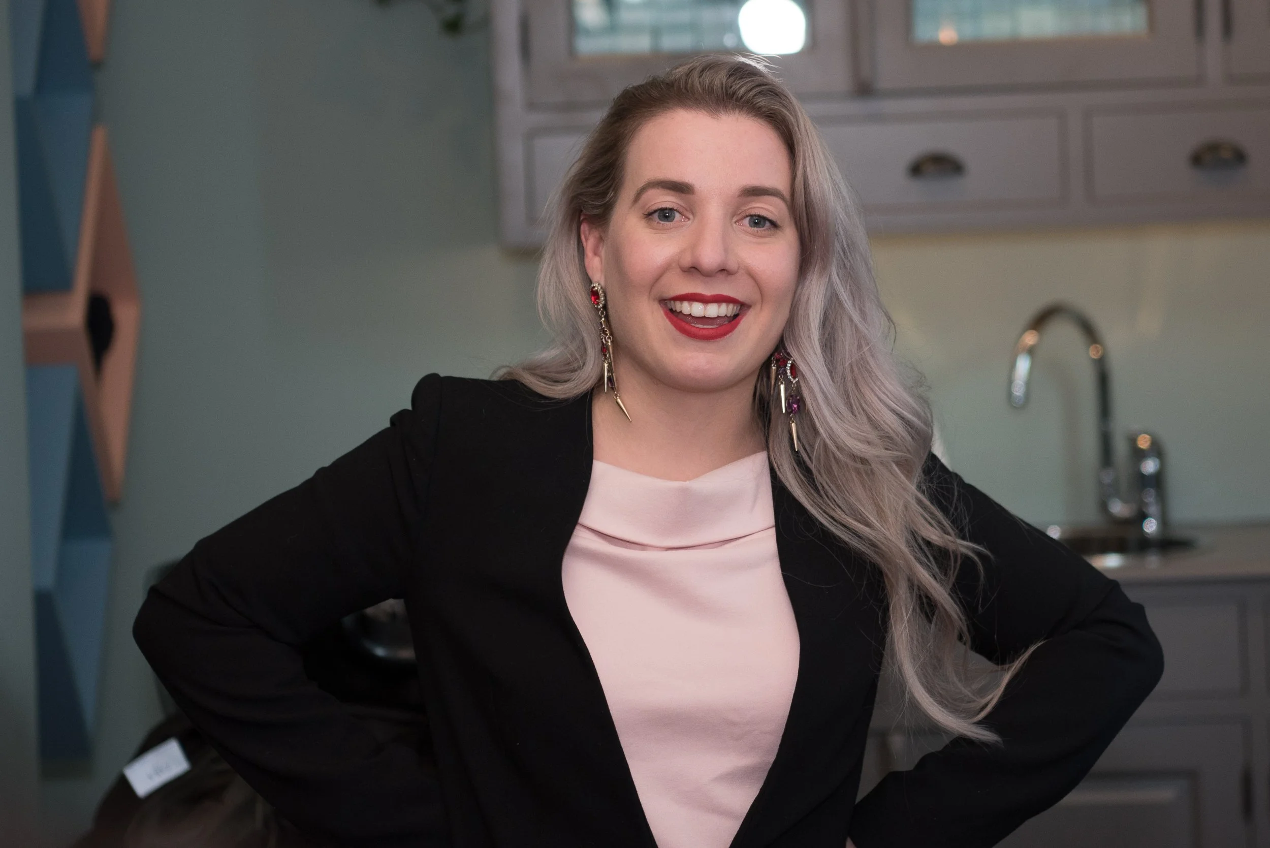Portret van een glimlachende vrouw in een zwarte blazer tijdens een feestelijke bijeenkomst.