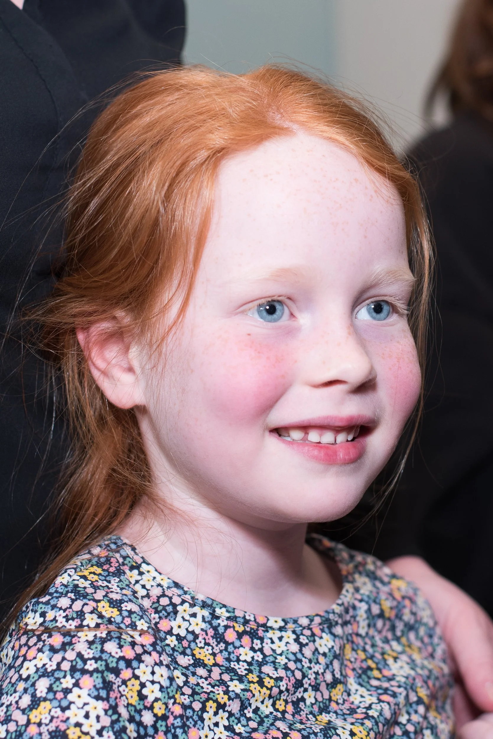 Spontaan en puur portret van een lachend roodharig meisje tijdens een feestelijke bijeenkomst.