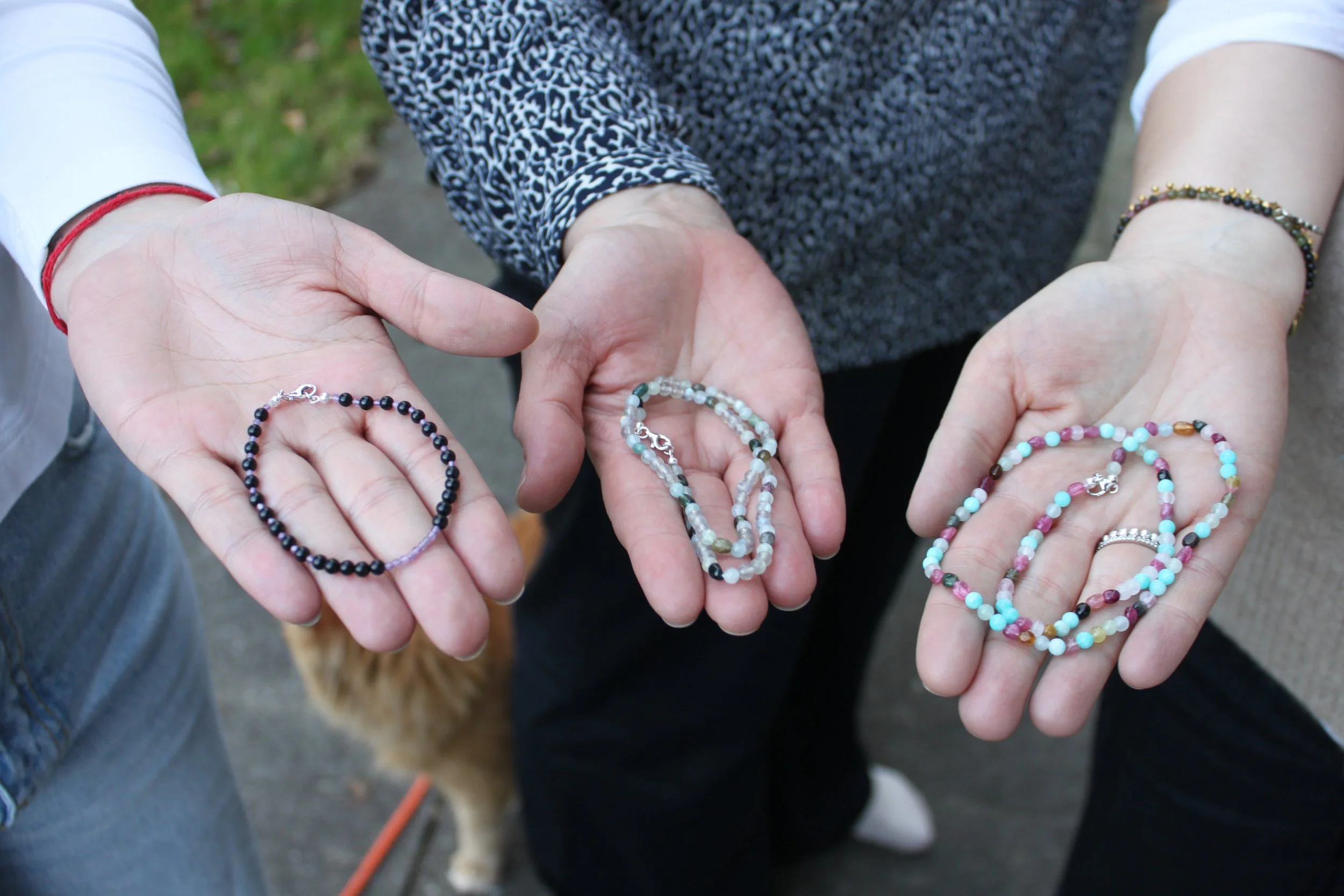 Menschen zeigen verschiedene bunte Schmuckarmbänder in ihren Handflächen.