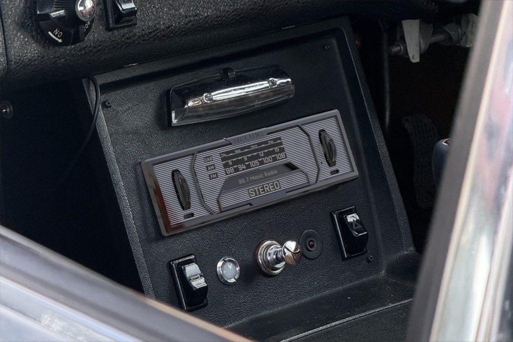 Close-up of a vintage car dashboard with a radio and some controls.