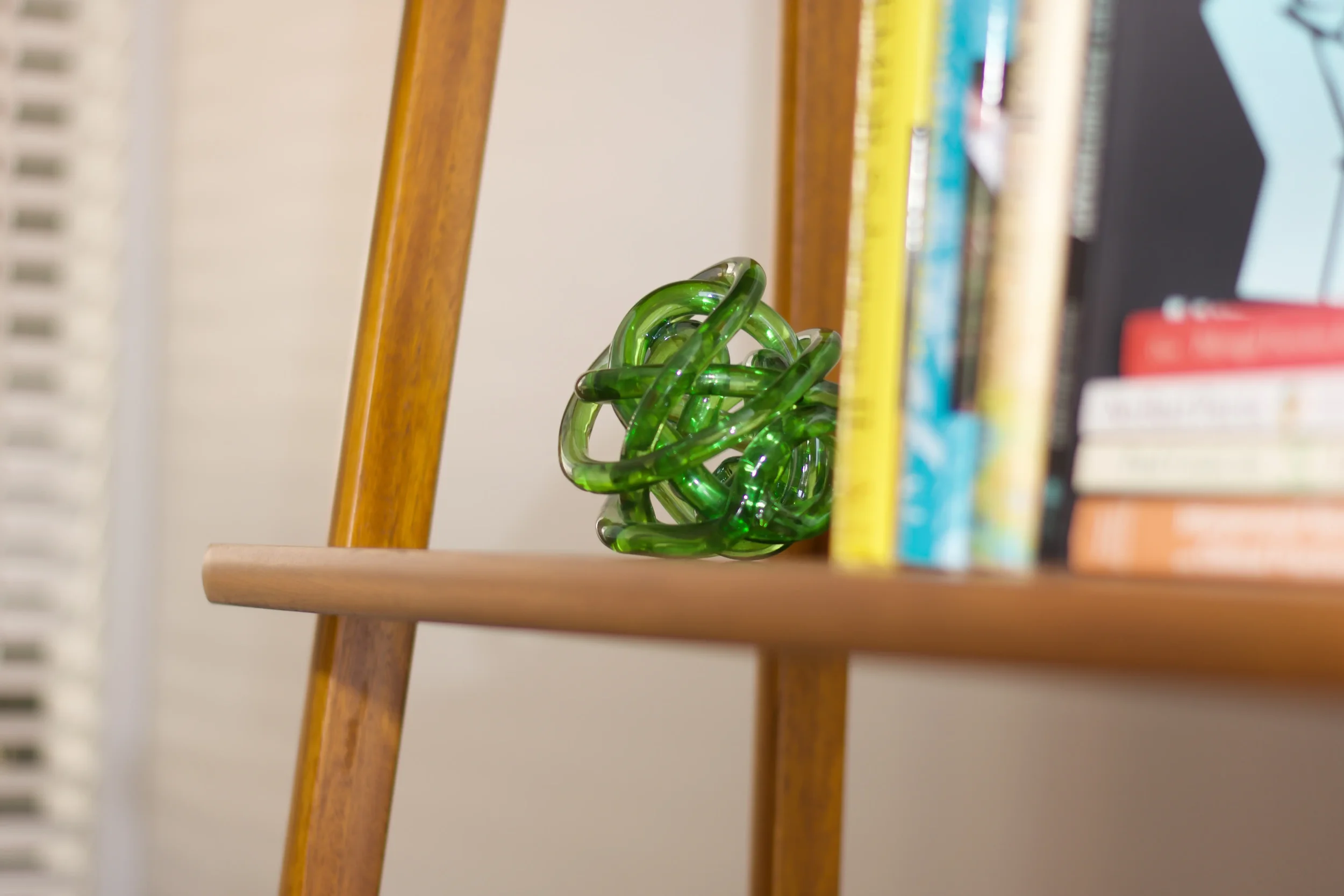 Green glass sculpture on bookshelf