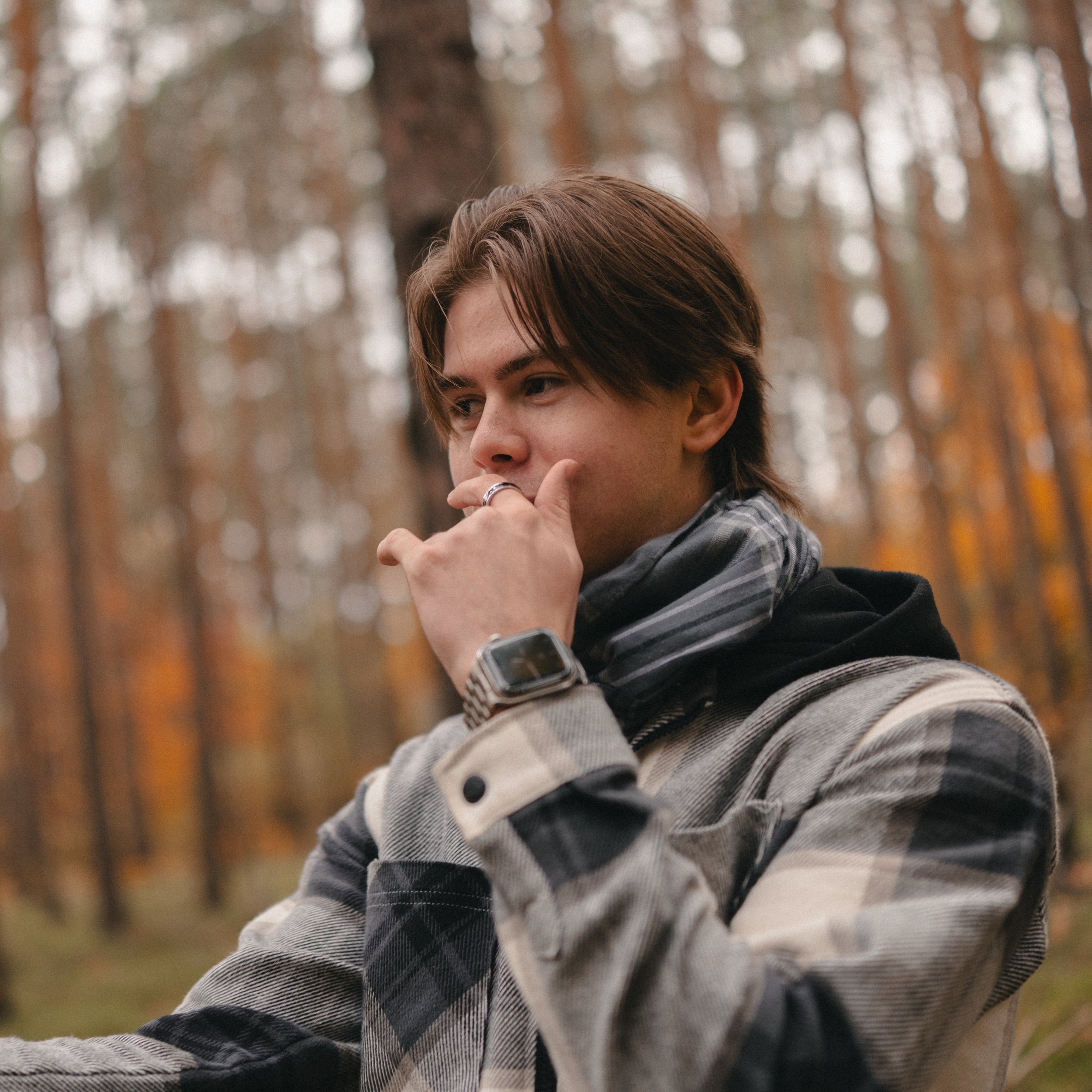 Fotograf Florian Herold im herbstlichen Wald, trägt karierte Jacke und Apple Watch