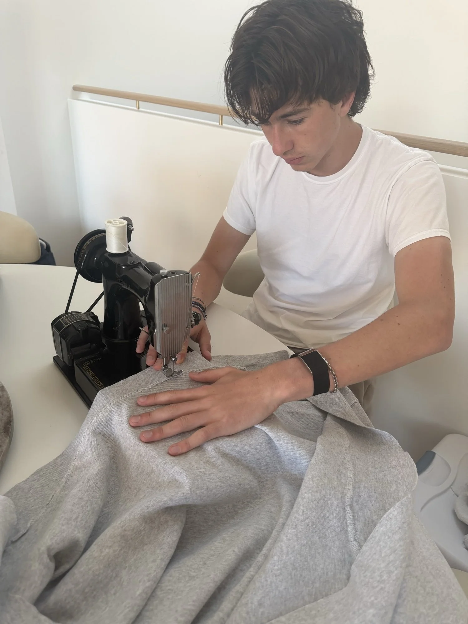 Brycen sewing reclaimed fabric into a blanket