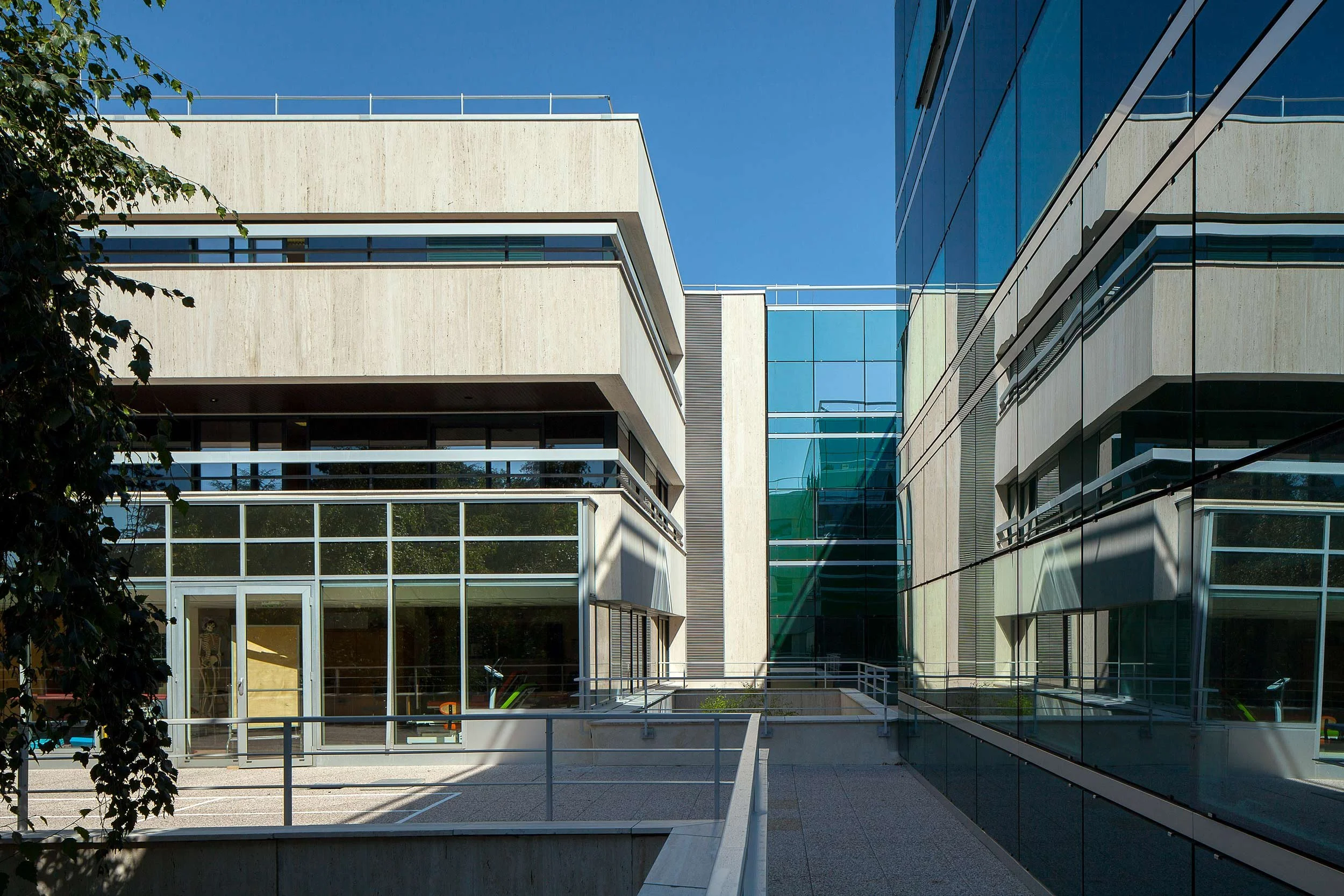 Bâtiments modernes avec façade en verre et en béton sous un ciel bleu.