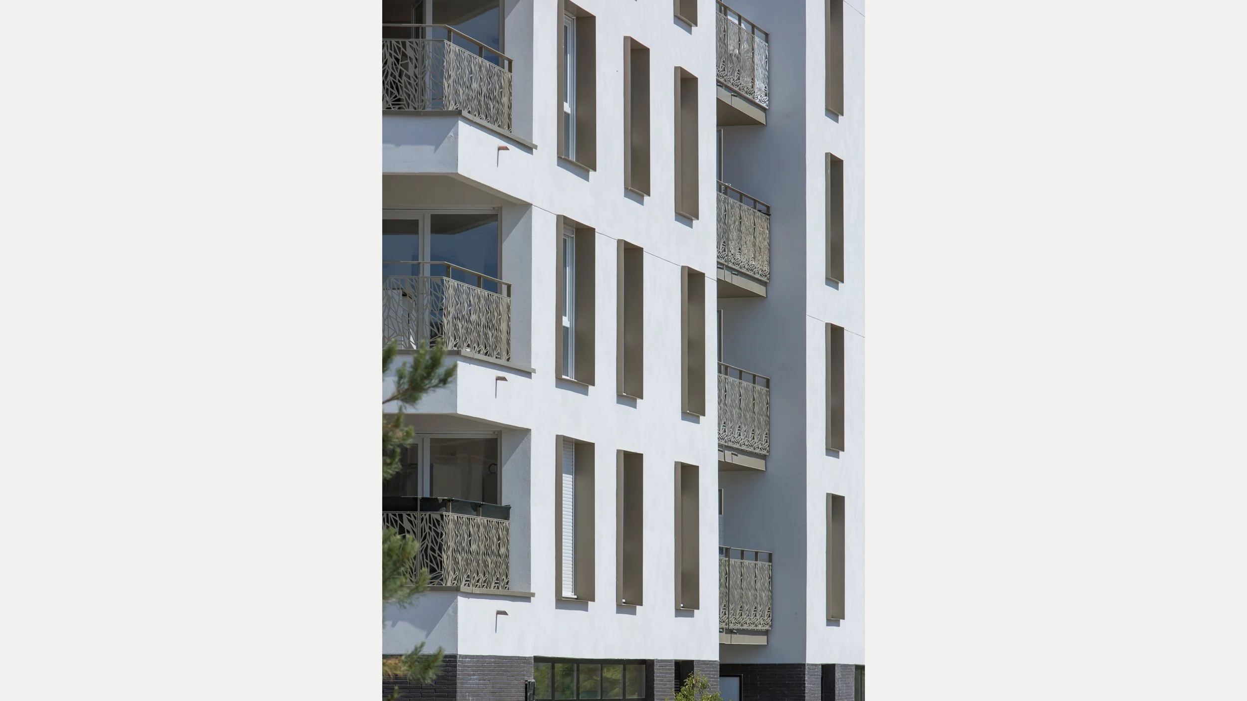 Façade d'un immeuble moderne blanc avec plusieurs balcons en fer forgé décoratif.