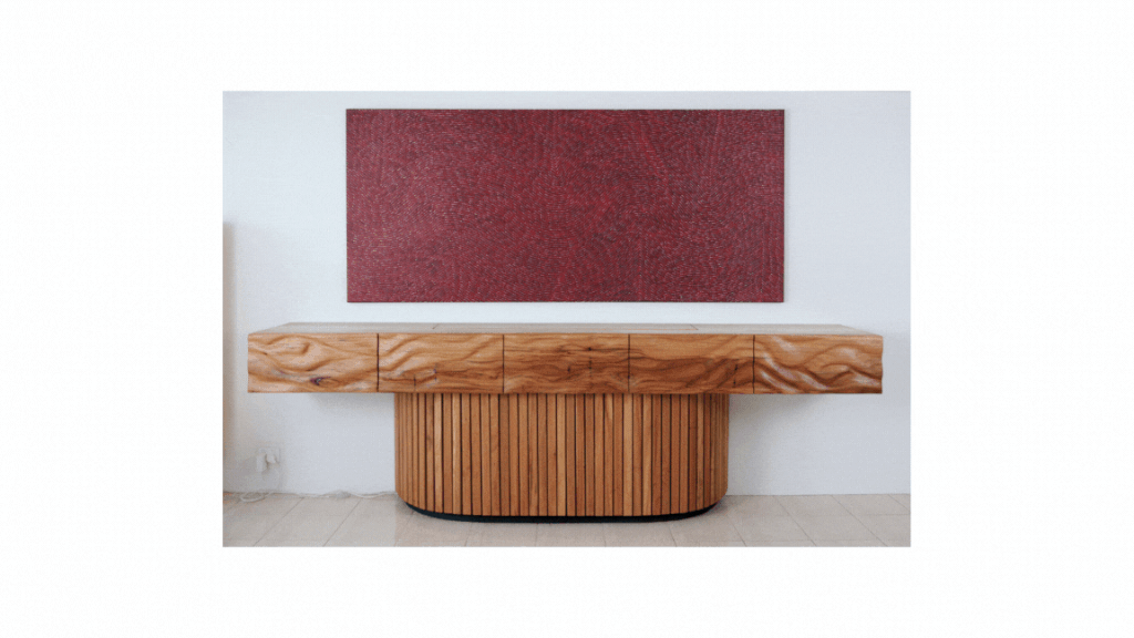 A wooden TV cabinet with a curved base against a white wall, with a large red textured artwork hanging above it.