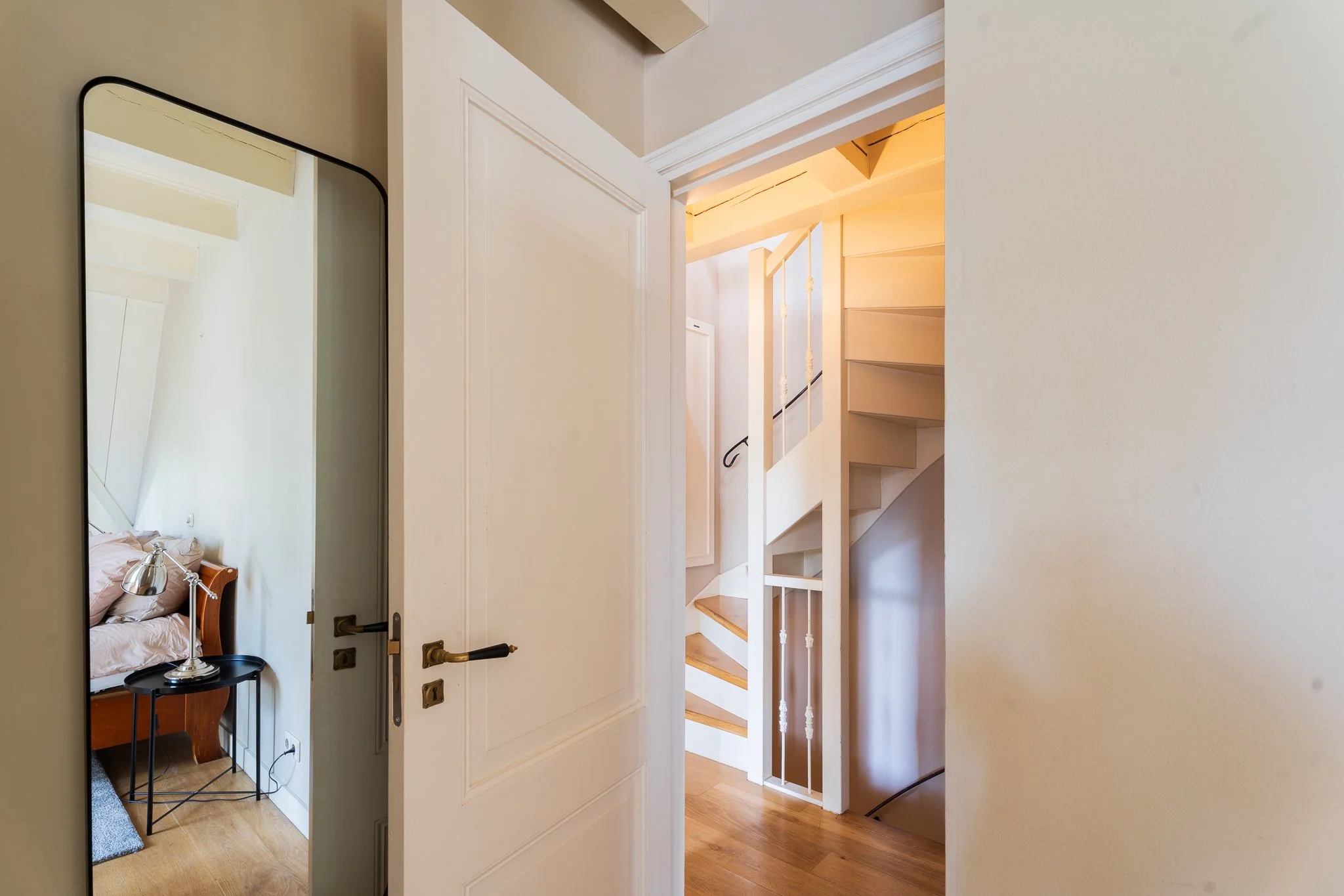 Interior view of a hallway with a staircase and an open door leading to a bedroom.