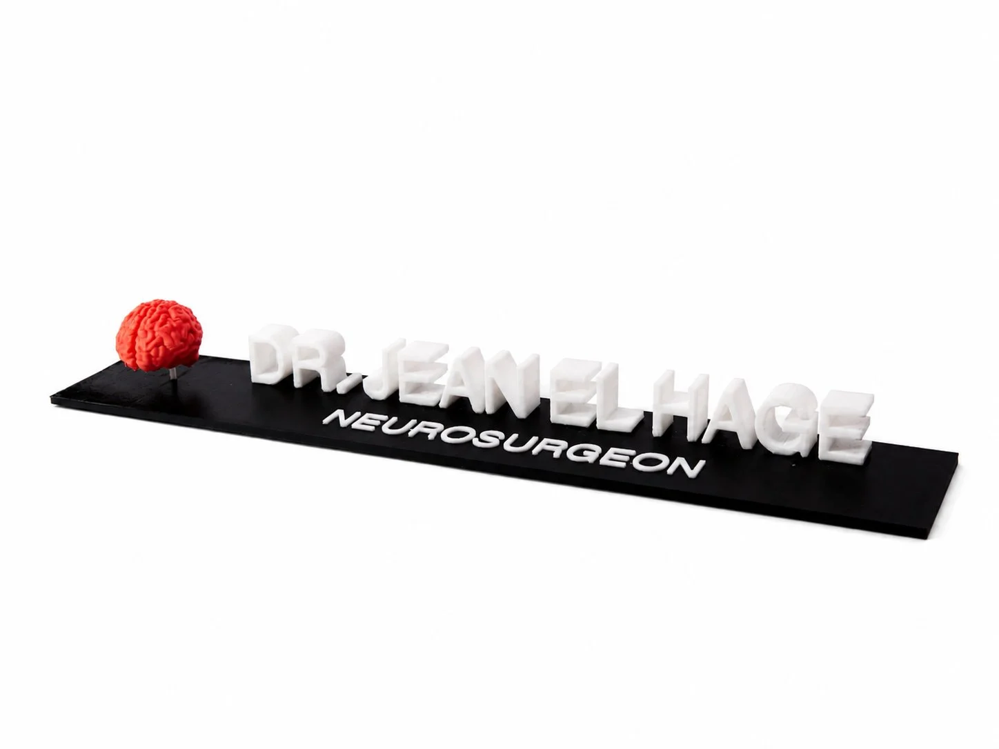 A decorative sign with the words "Dr. Jeanell Hage Neurosurgery" in white letters on a black base, and a red brain-shaped object on the left side.
