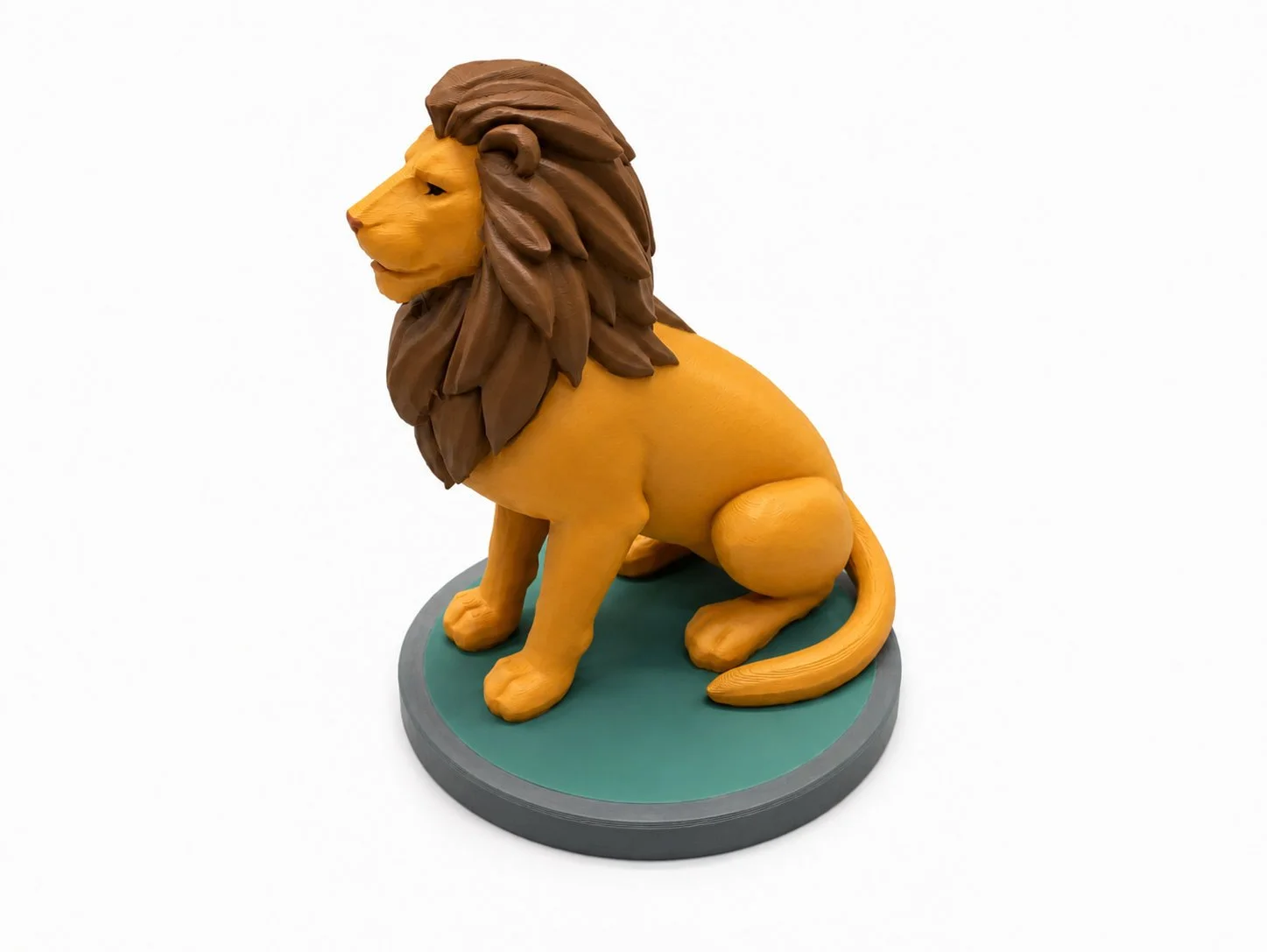A realistic sculpture of a sitting lion, made of a material that looks like painted clay, on a circular green and gray base.