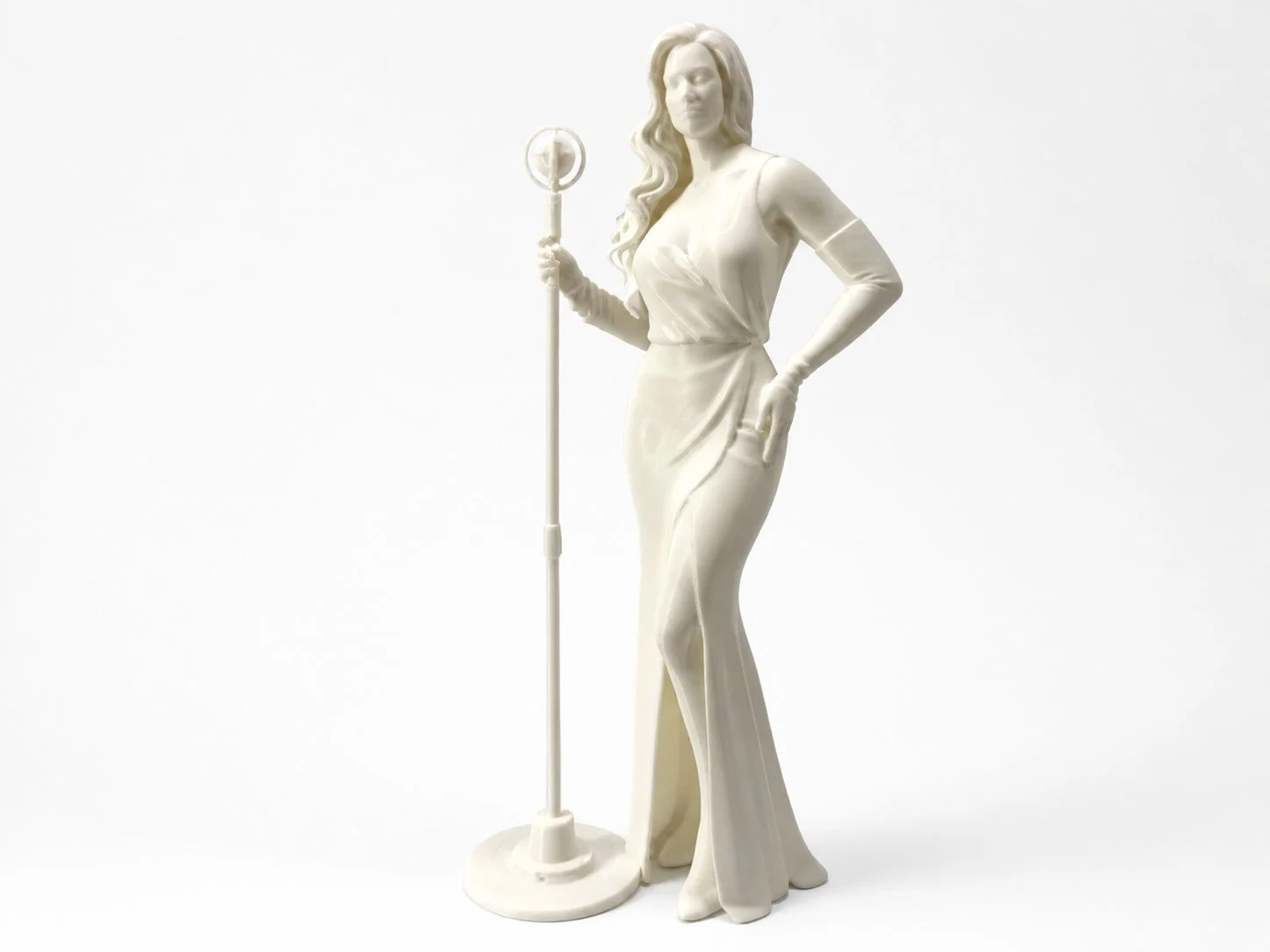 White statue of a woman in a long dress holding a vintage microphone, standing with one hand on her hip, on a white background.