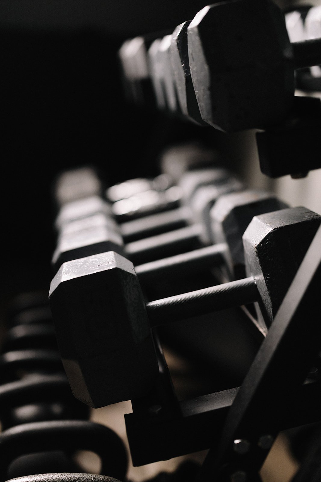 Close-up of black dumbbells stacked on a rack implying that fitness is a good coping skill when you get sober
