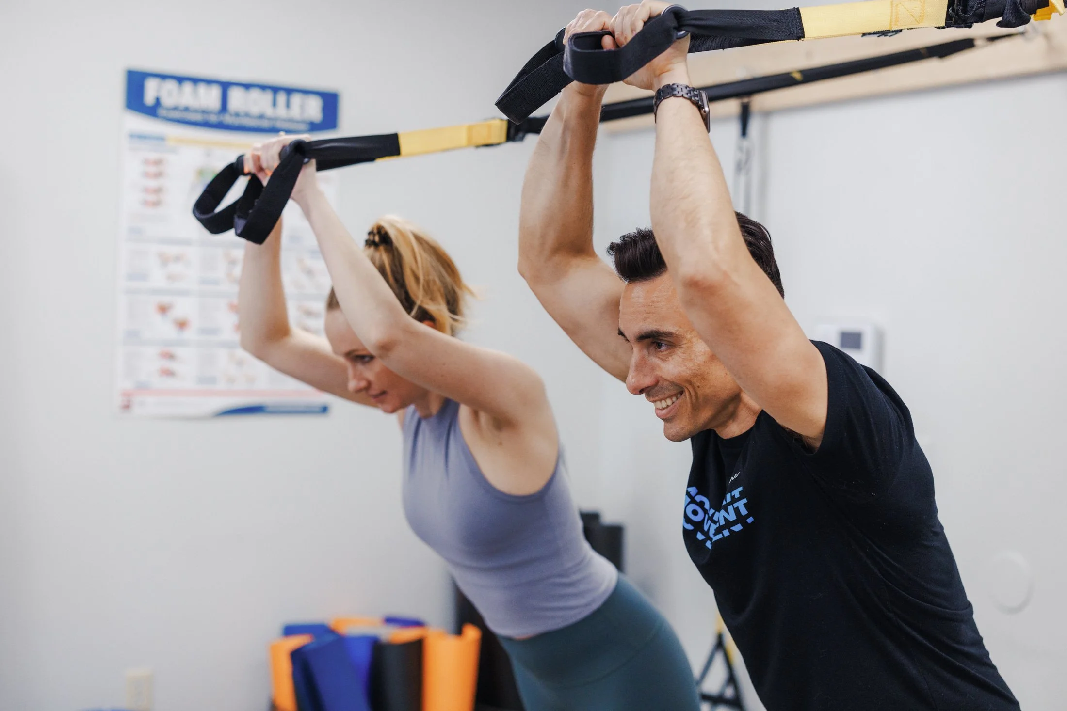 Two sober  people, a woman and a man, exercising with suspension straps in a fitness class, smiling and focused