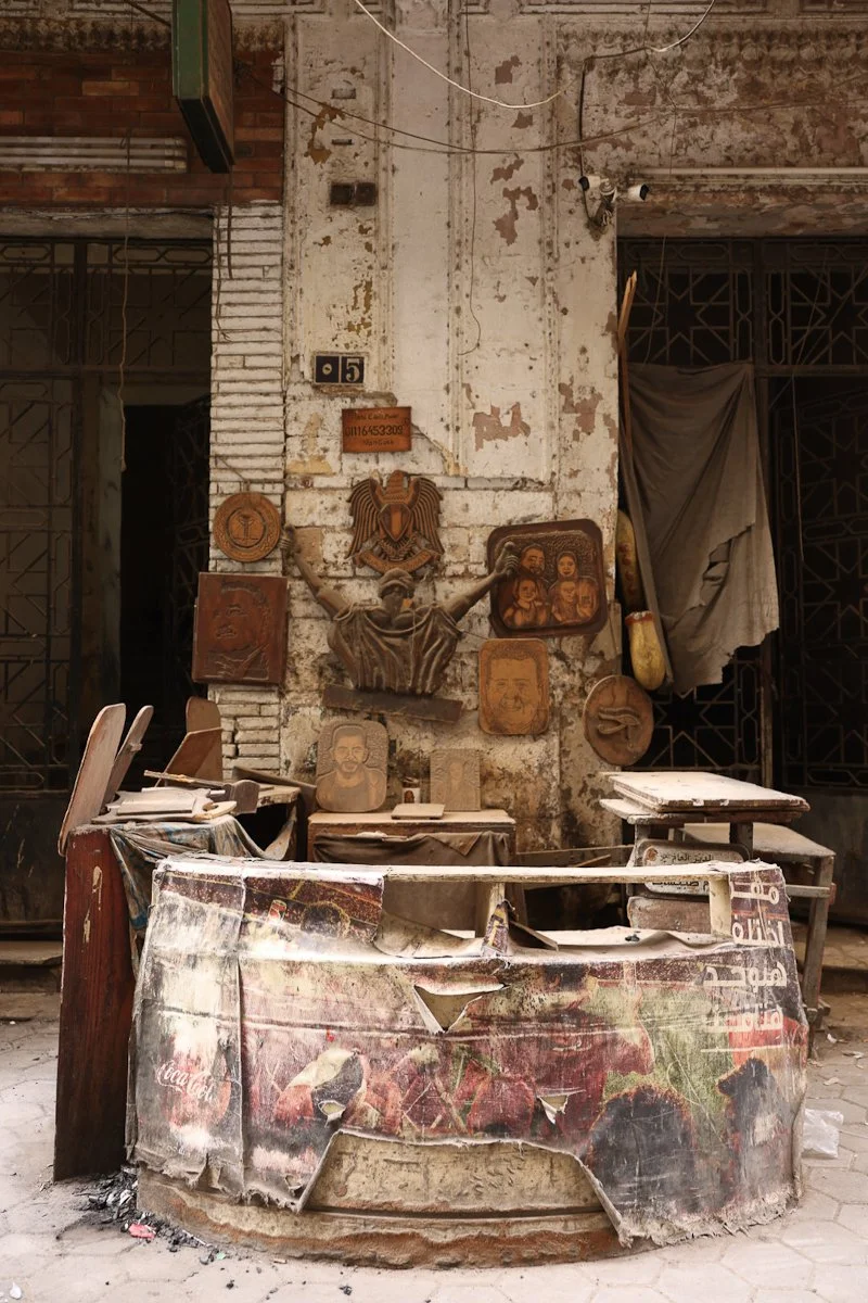Wall of carved wooden plaques above cluttered artisan workspace