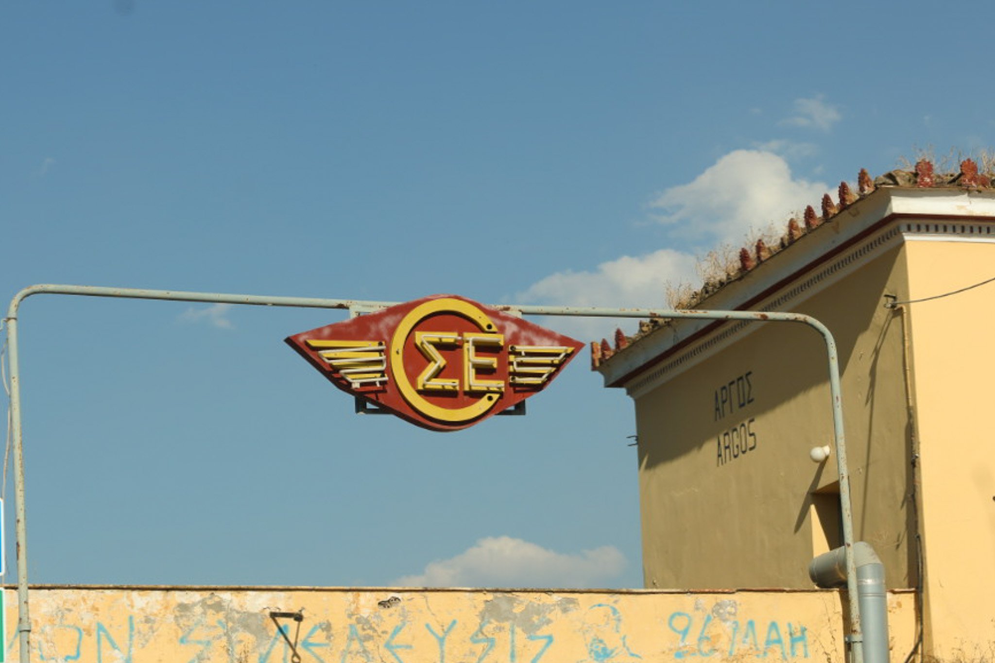Abandoned train station in Argos with a faded mid‑century sign.