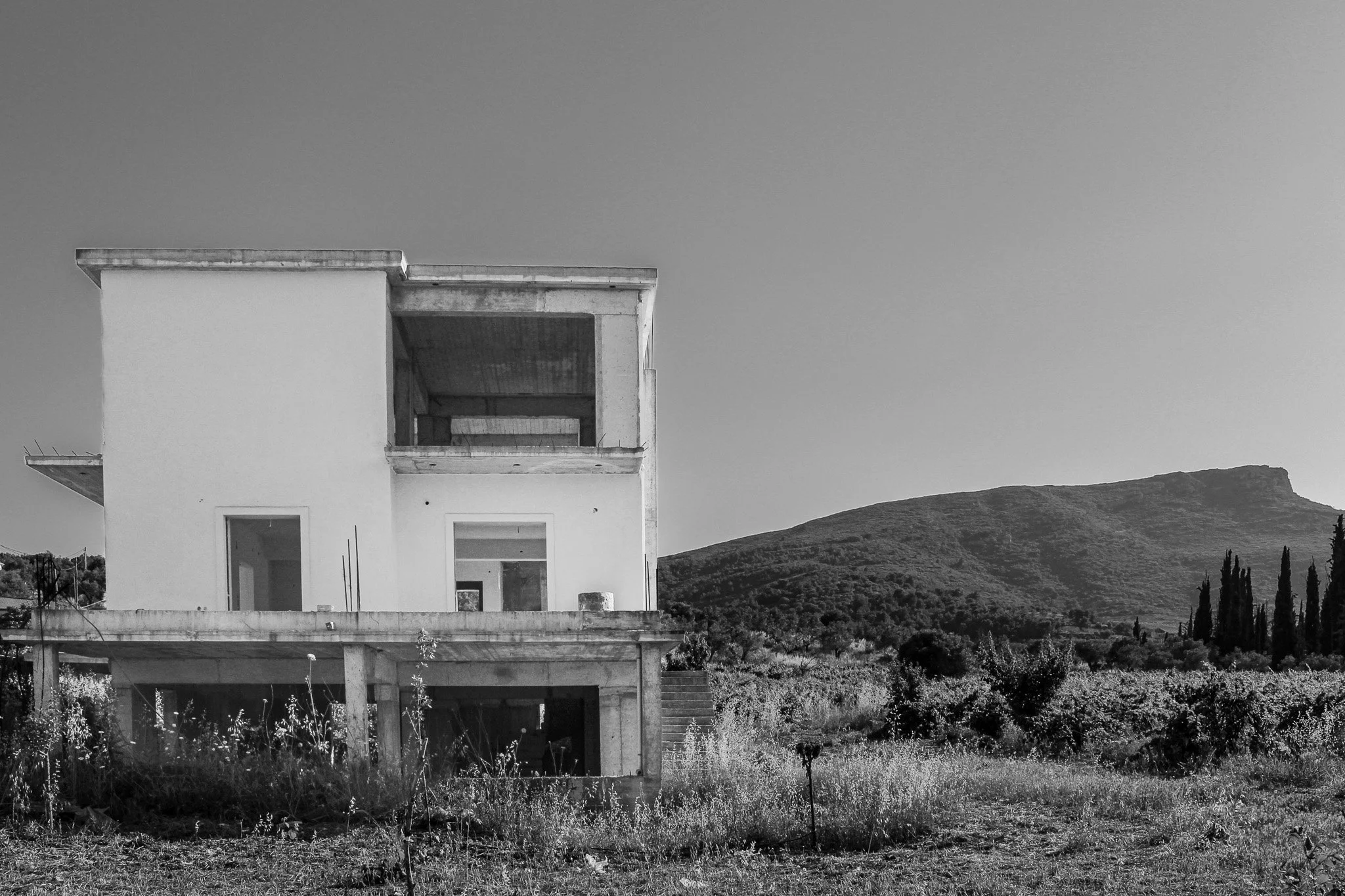 Abandoned new‑construction concrete home in Ancient Nemea.