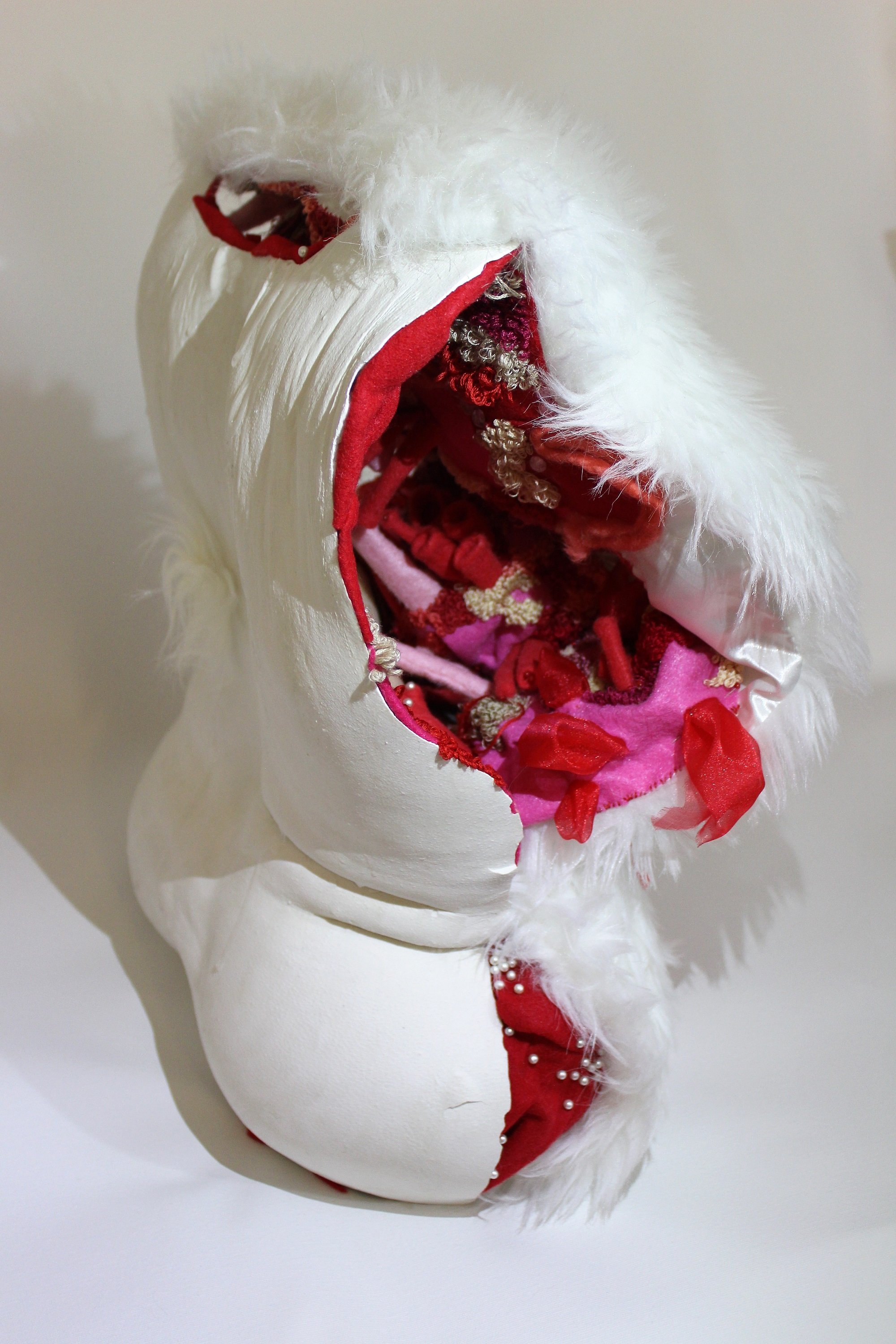 Close-up of a white torso showing a detailed interior filled with colorful fabric and decorative items.