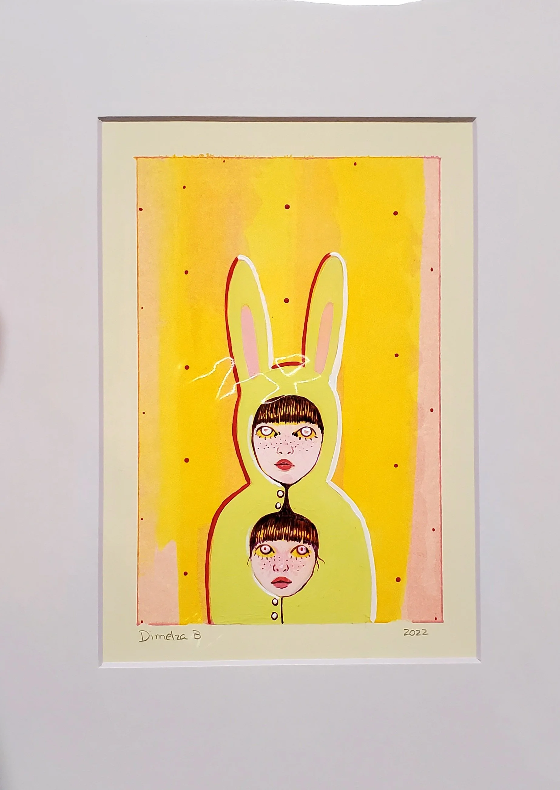 Colorful artwork featuring a girl with dark hair and large freckled face, with bunny ears extending above her head, set against a yellow background with small red dots. The artwork is signed 'Dimelza B' and dated 2022.