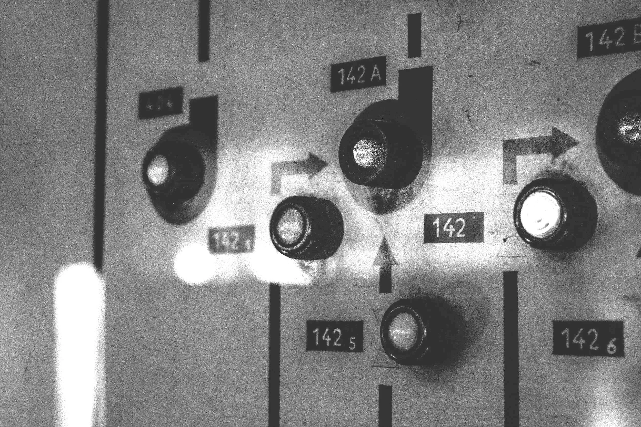 Black and white photo of a control panel with multiple switches, knobs, and labels, including numbers like 142, 142A, 142B, 1425, and 1426.