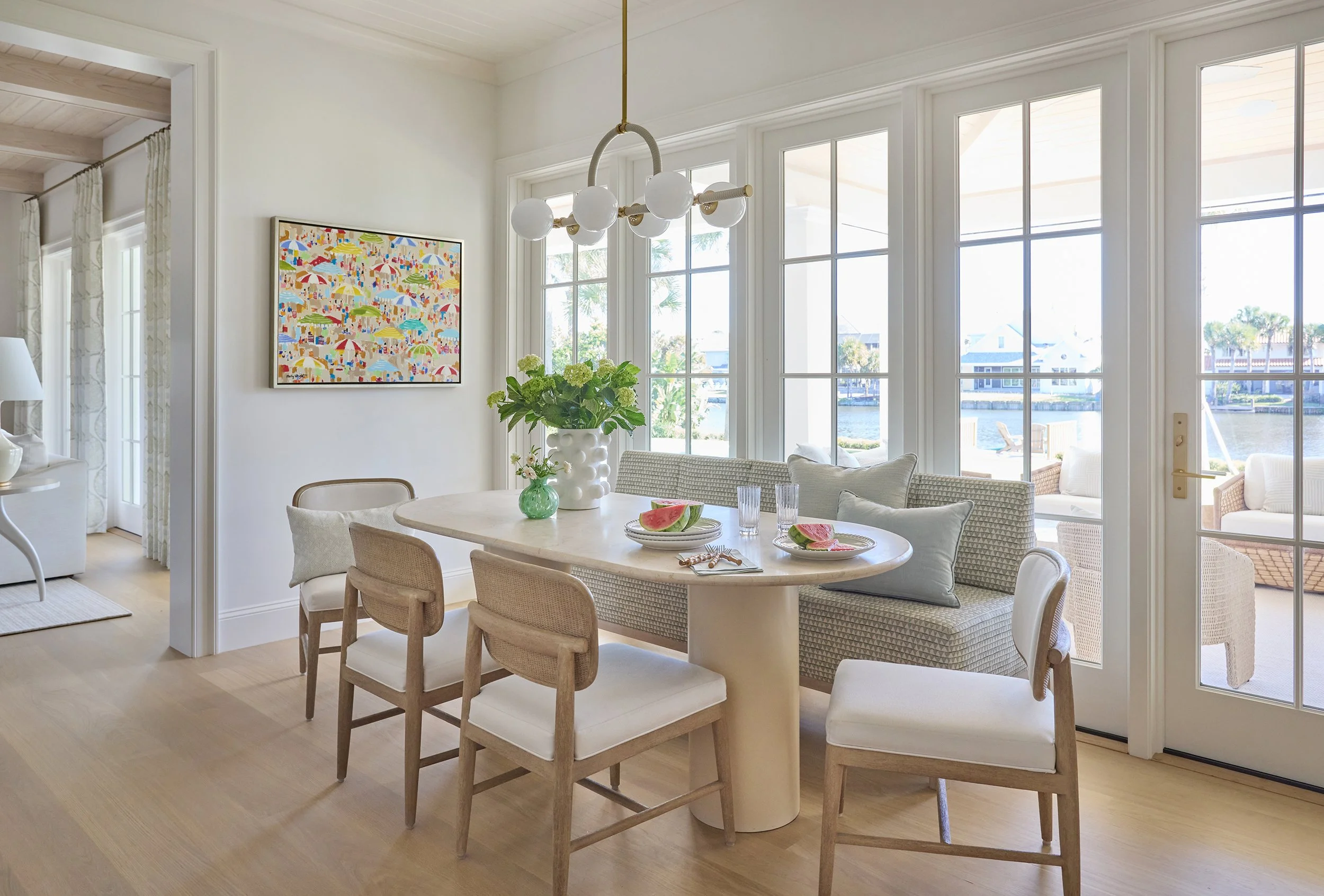 Bright dining room with round table, six chairs, large windows showing outdoor view