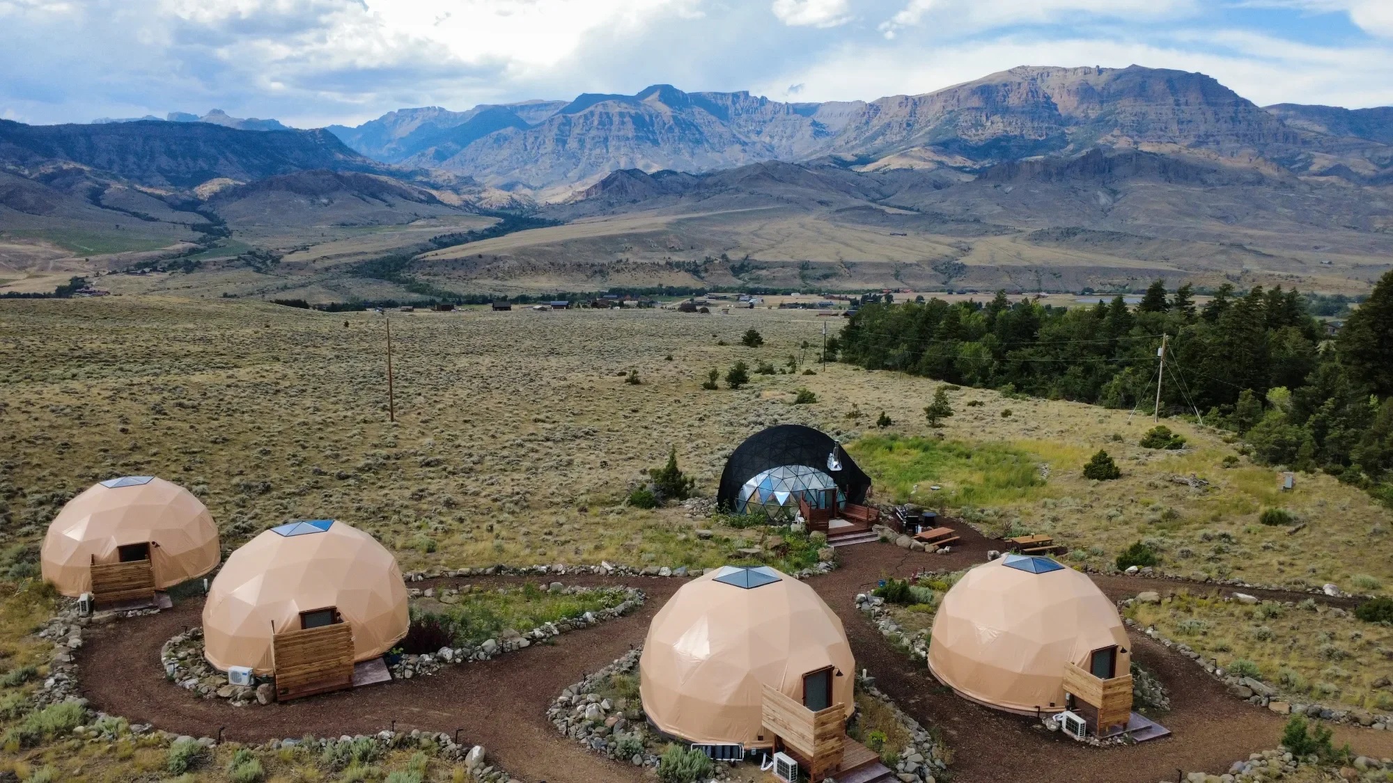 Four geodesic domes clustered together in a desert landscape with mountains in the background.