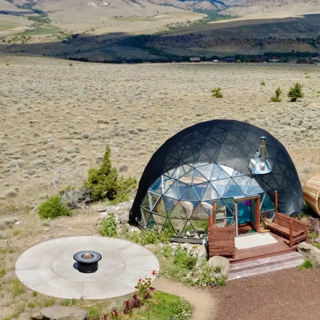 A geodesic yoga dome studio with circular fire pit area nearby at Pure Heart Retreat in Wapiti, WY.