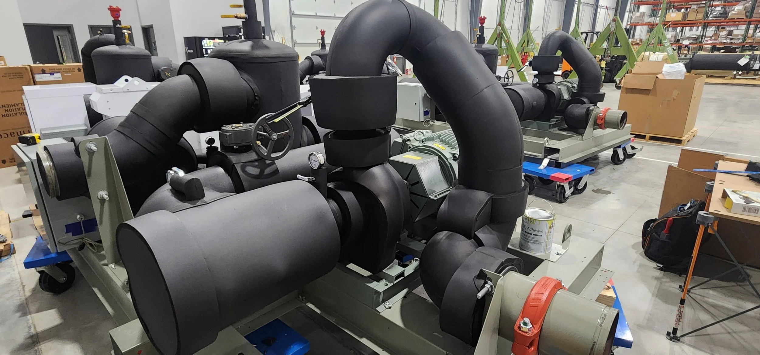 Industrial machinery with black pipes and valves in a warehouse.