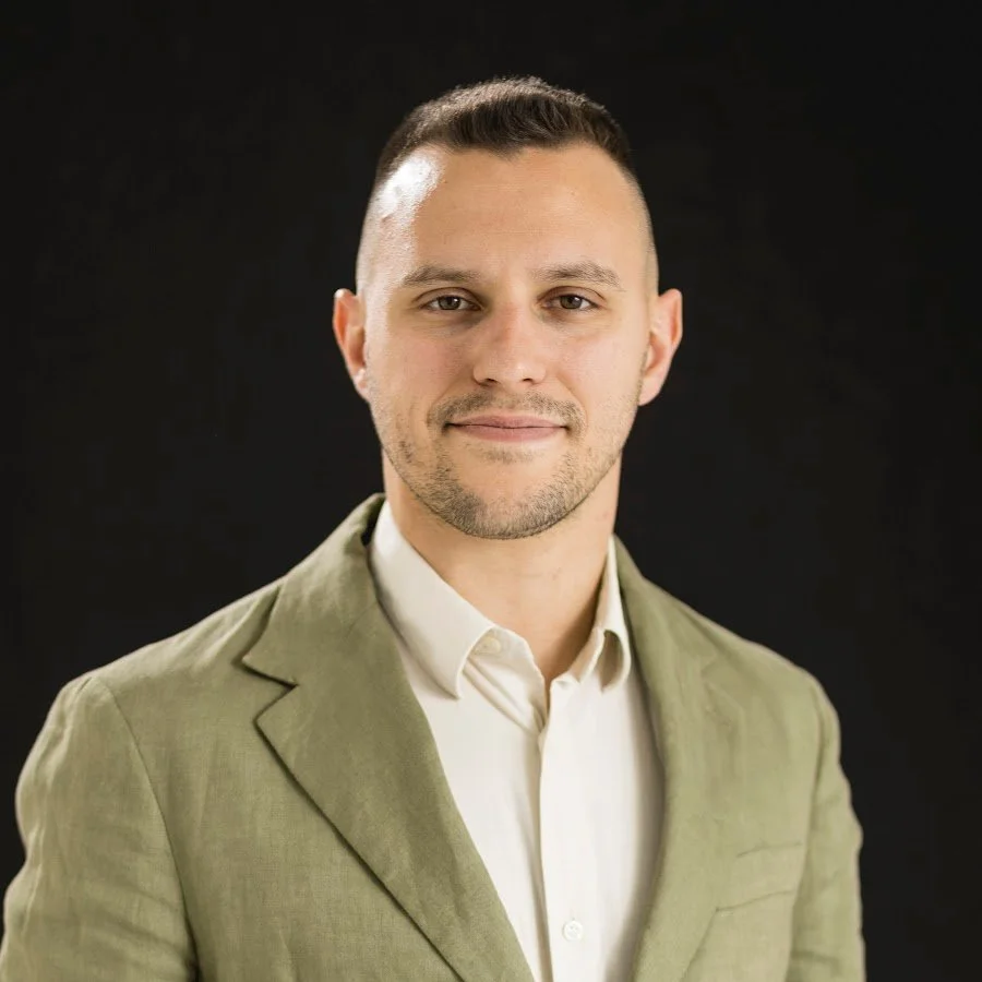 Uomo con giacca verde chiaro e camicia bianca, sfondo nero, fotografia professionale.