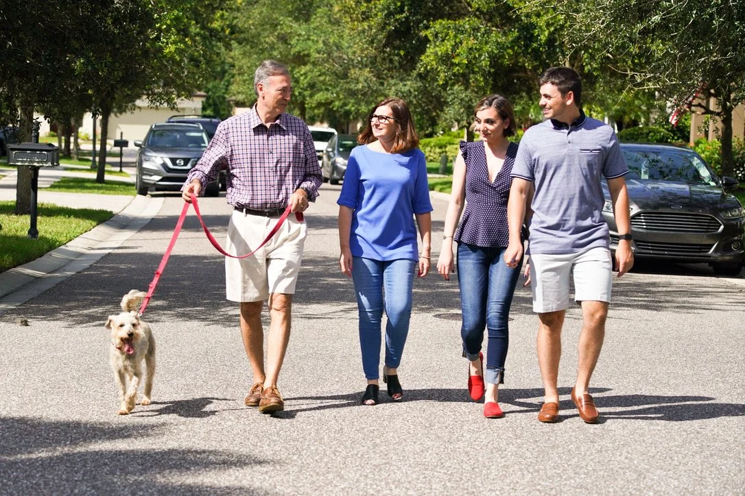 A group of people walking together on a suburban street, with one man walking a dog.