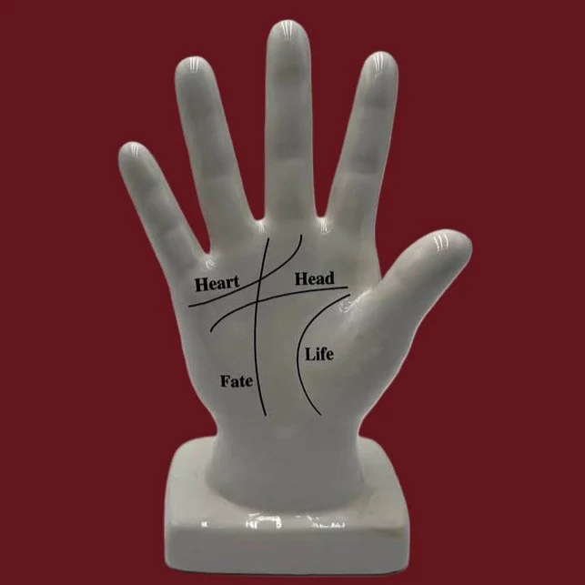White ceramic hand with palmestry lines painted on it.