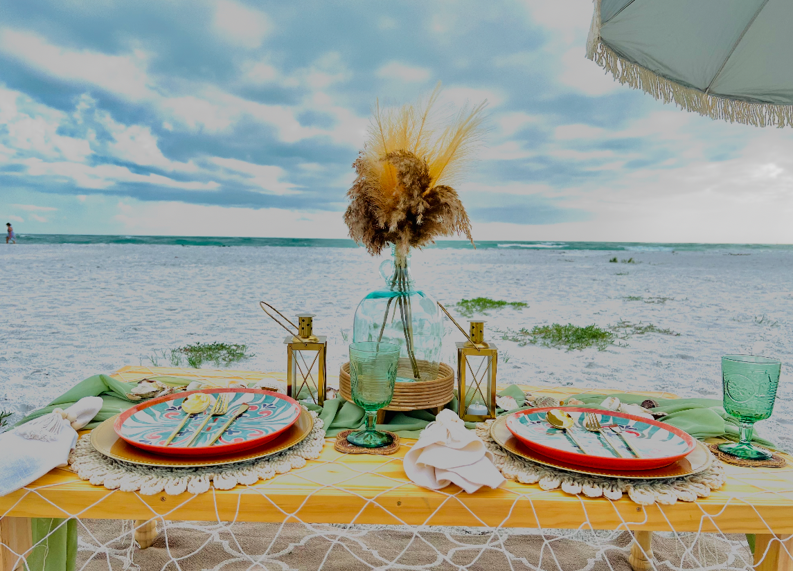 Elegant beachside table setting styled by Janice, featuring a yellow tablecloth, florals, and ocean backdrop.