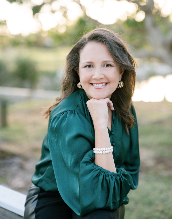 Janice Rodriguez, founder of Perfect Fit Media, smiling outdoors in a green blouse and pearl bracelet.