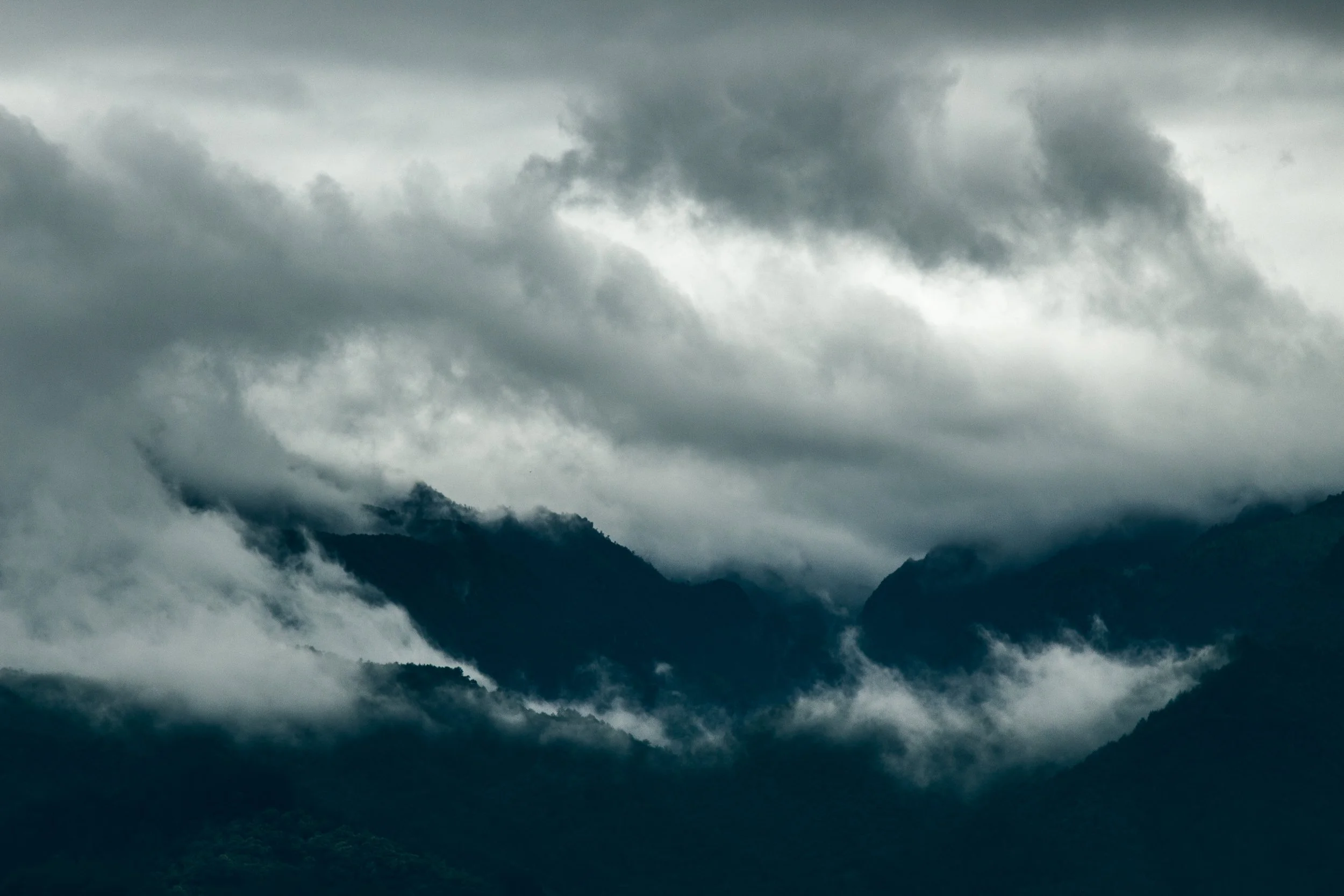 Cloud-covered mountains in a misty, overcast setting.