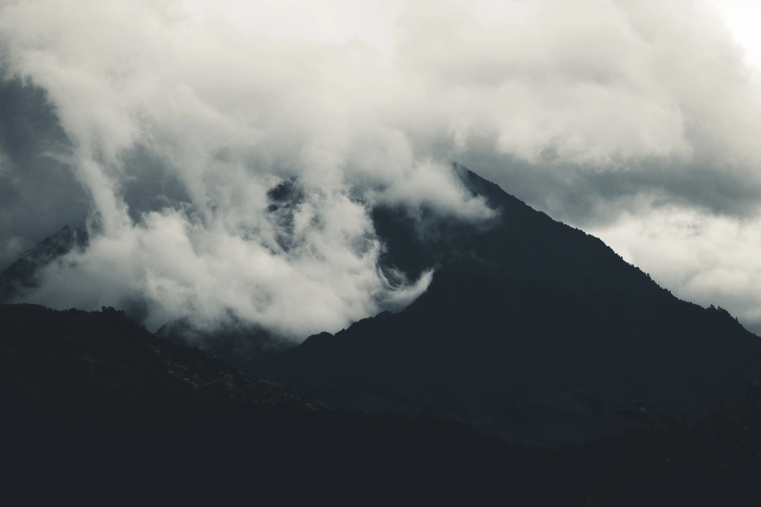 Cloud-covered mountain peaks in a dark, moody landscape.