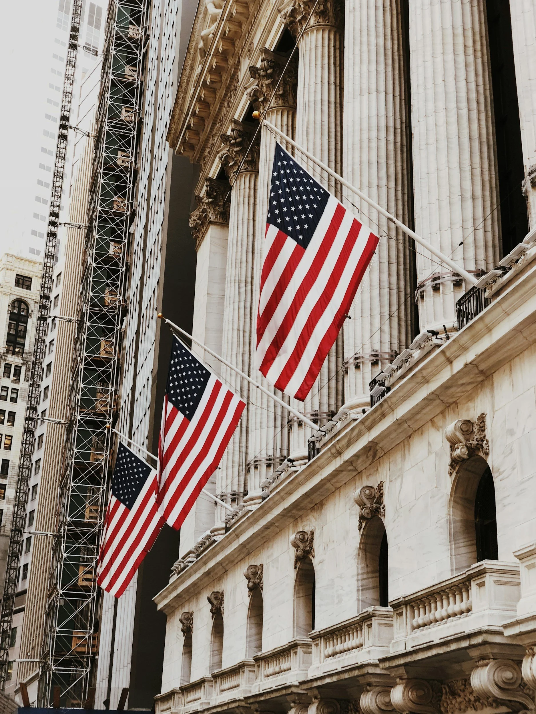 A row of American flags line a classical building