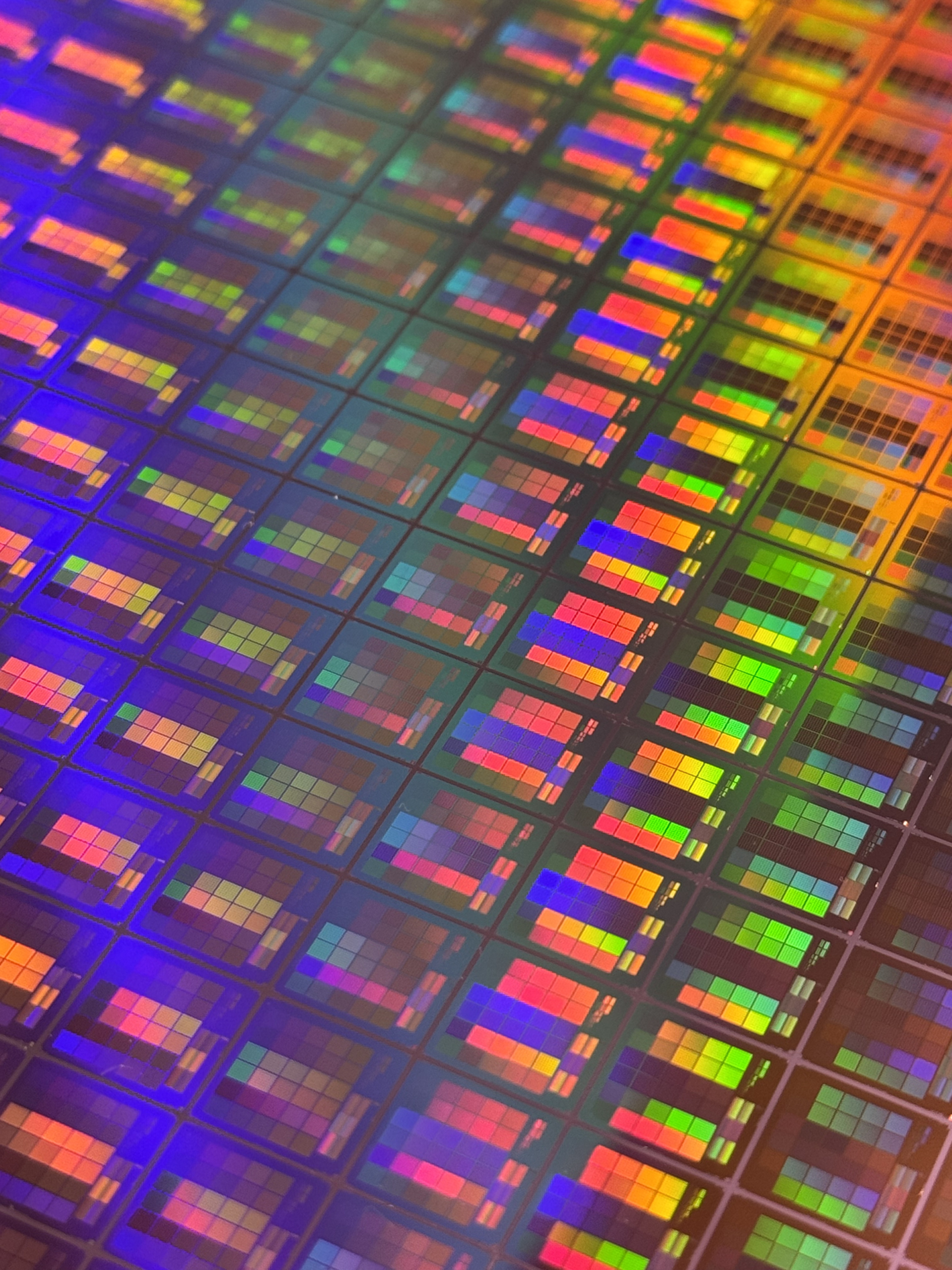 A close-up view of a nanophotonic wafer with colorful geometric patterns and circuitry.