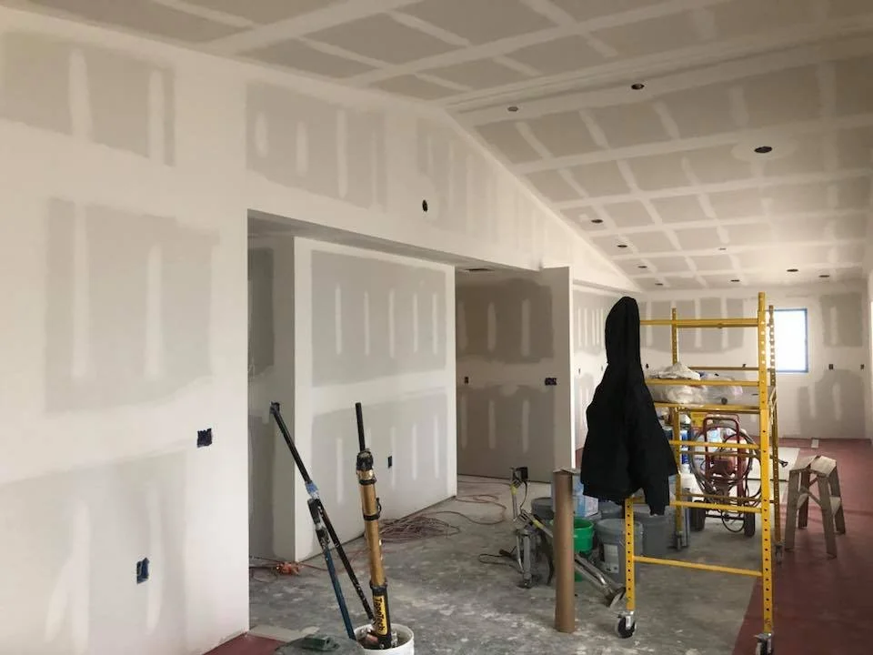 Interior view of a room under construction with unfinished drywall and tools.