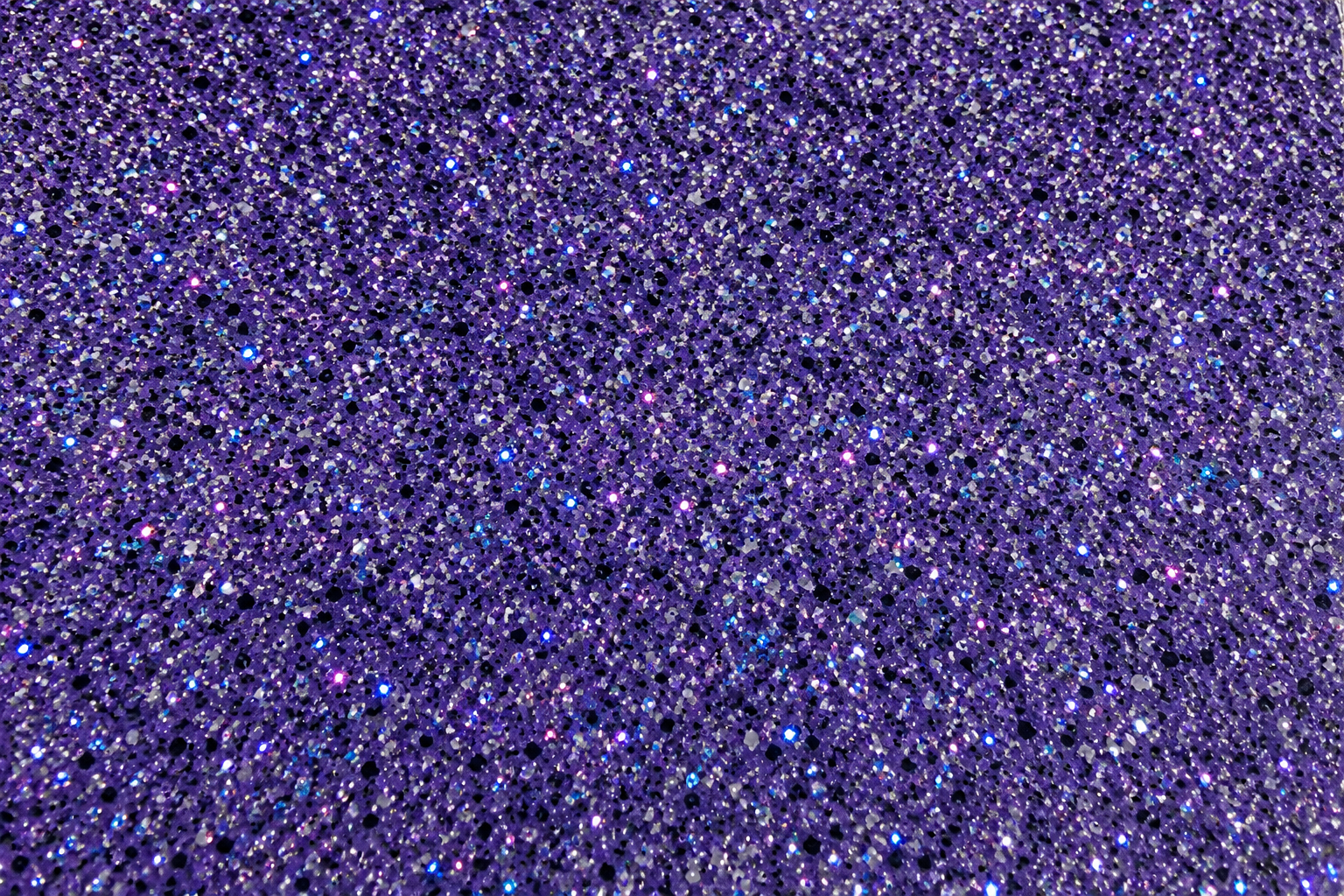 Close-up of purple glitter with various reflective specks.