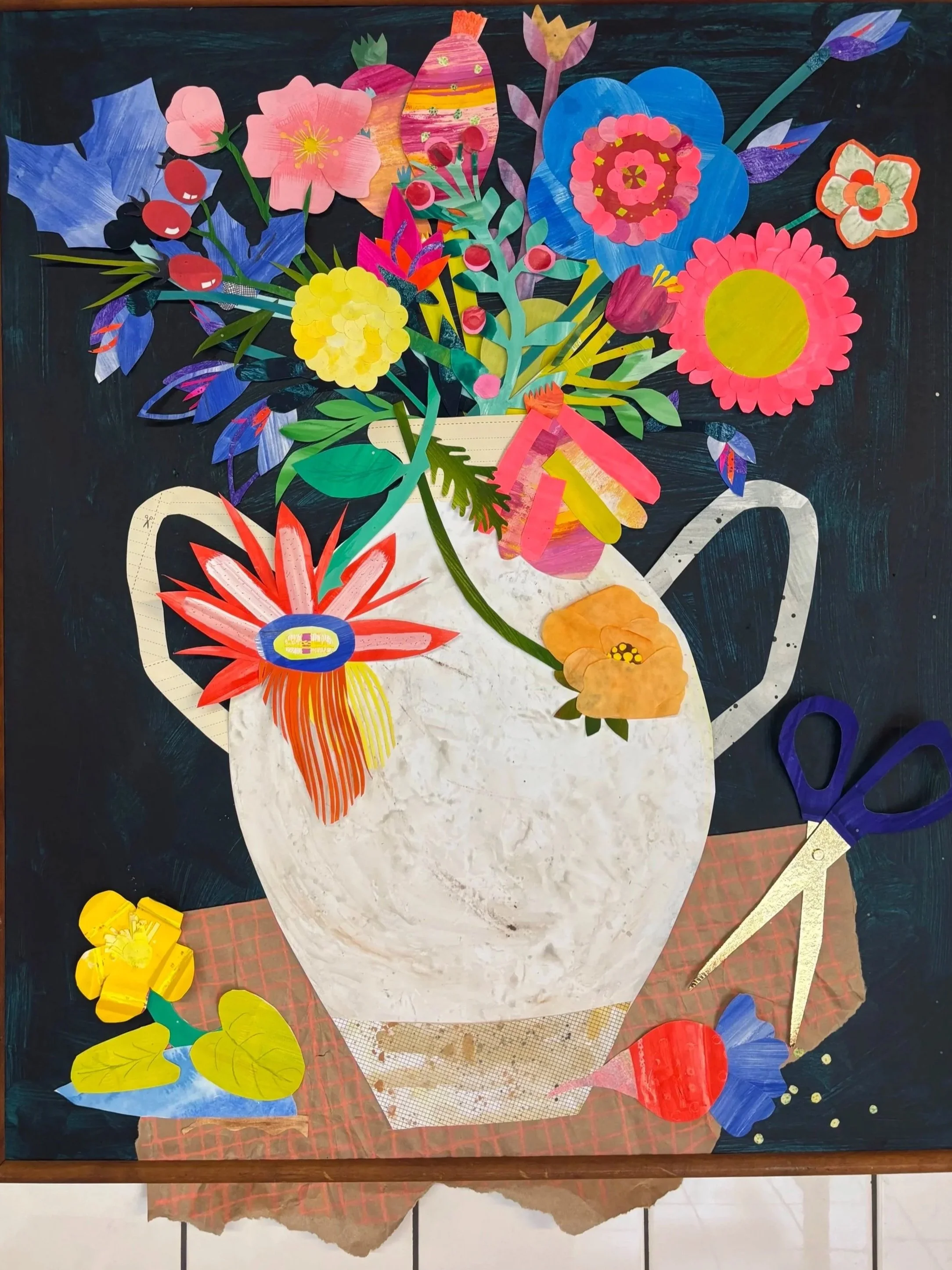 Collage artwork of a vase filled with colorful paper flowers, scissors, and leaves, set on a checkered tablecloth.