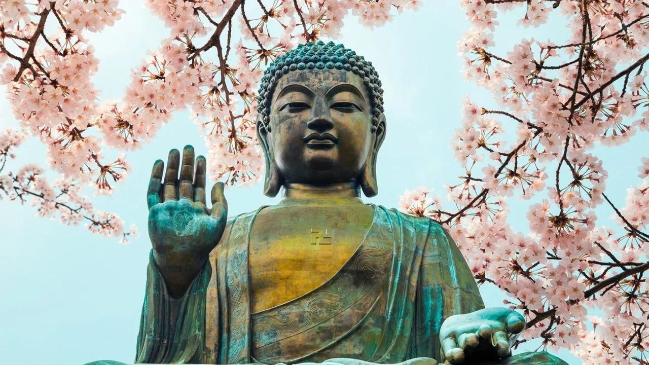 Buddha statue in front of pink blossoms