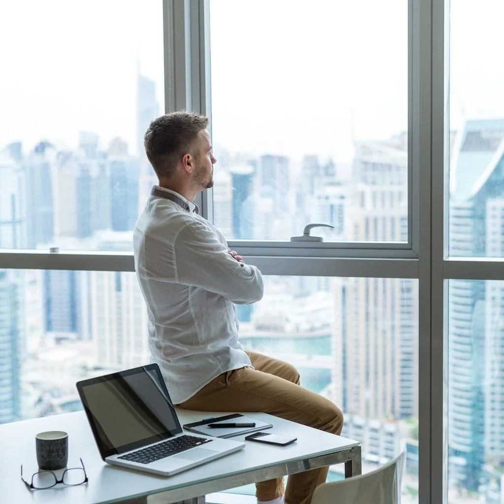 Young businessman in office looking out over city