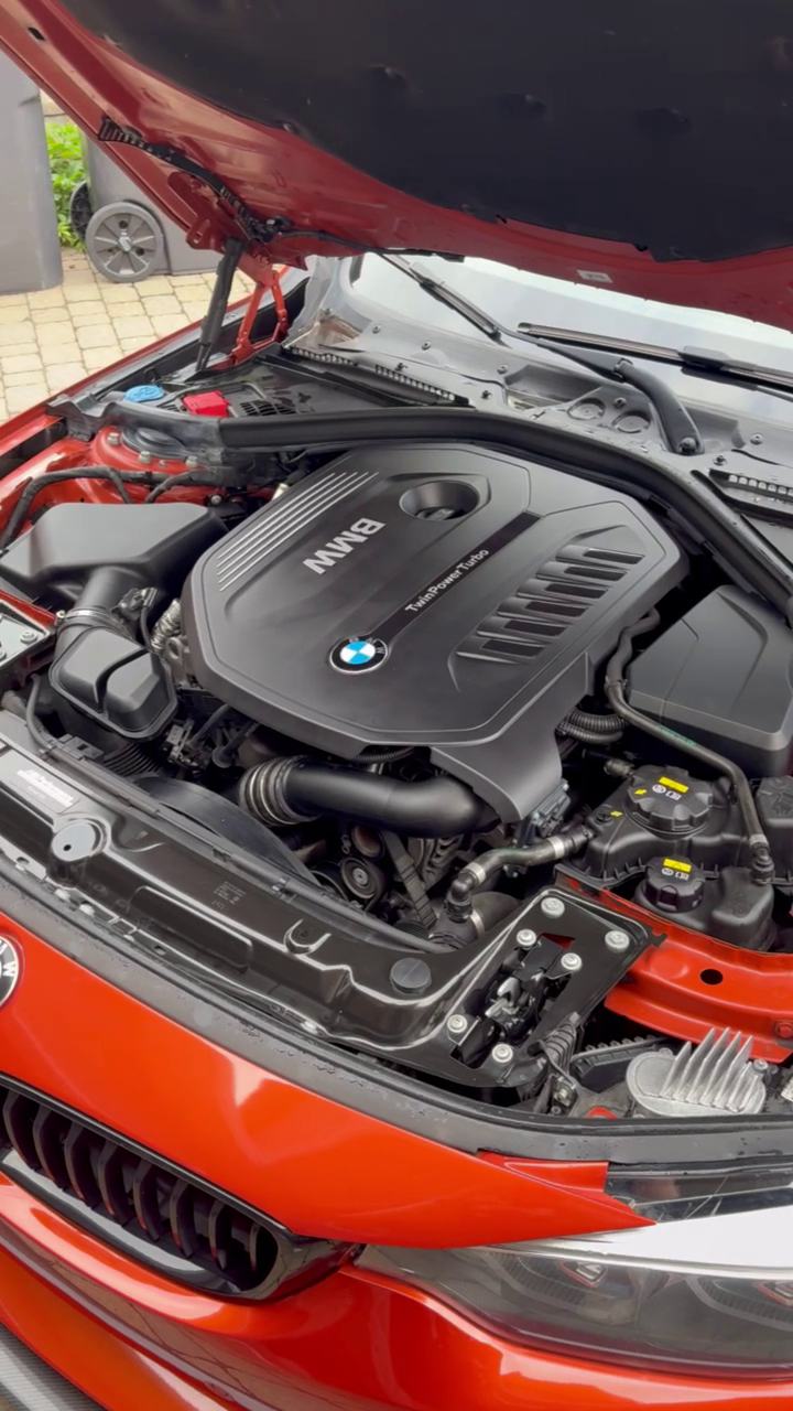 Moteur BMW TwinPower Turbo dans le capot d'une voiture rouge.