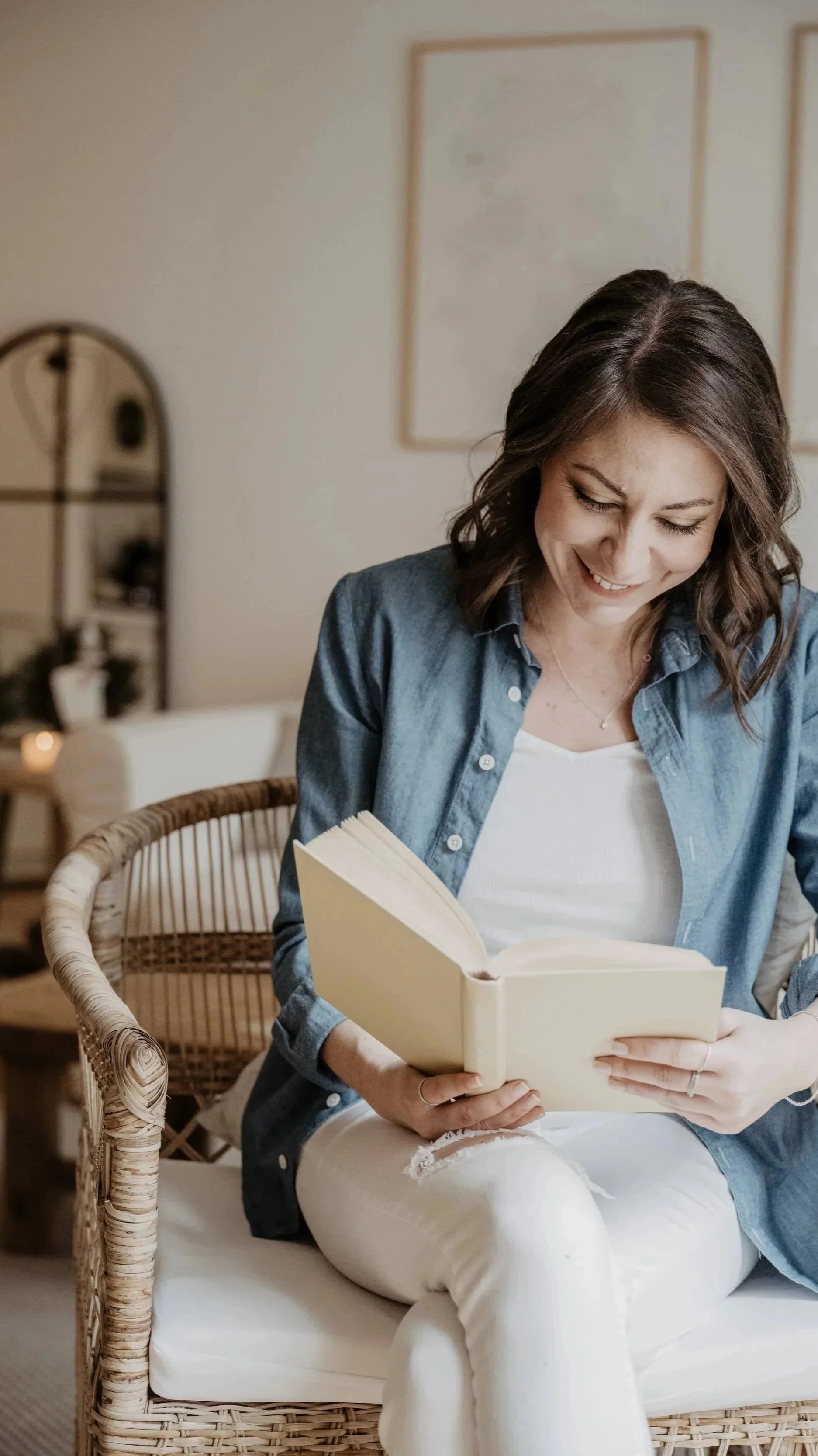 Eine lächelnde Frau liest ein Buch in einem Wohnzimmer.Klientin erhält einfühlsame psychologische Unterstützung bei Angst und Lebenskrise in Luzerner Praxis