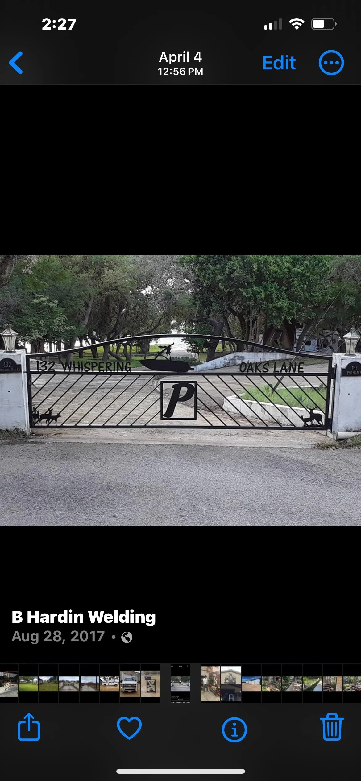 Gated entrance with decorative ironwork featuring a silhouette of a dog in a boat, trees in the background, and text reading '132 Whispering Oaks Lane' and 'P' for parking.
