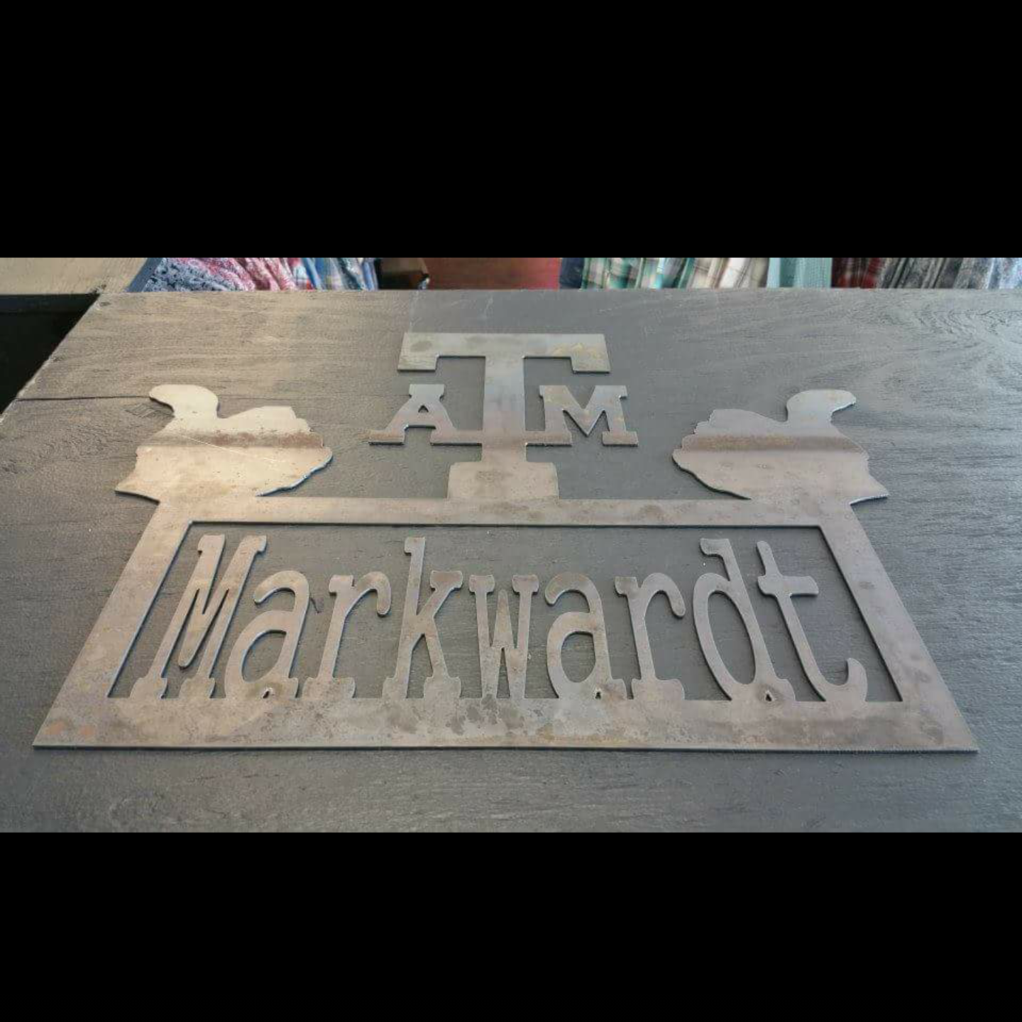 Metal sign with the words 'Texas A&M University' and the university's logo on a wooden table.