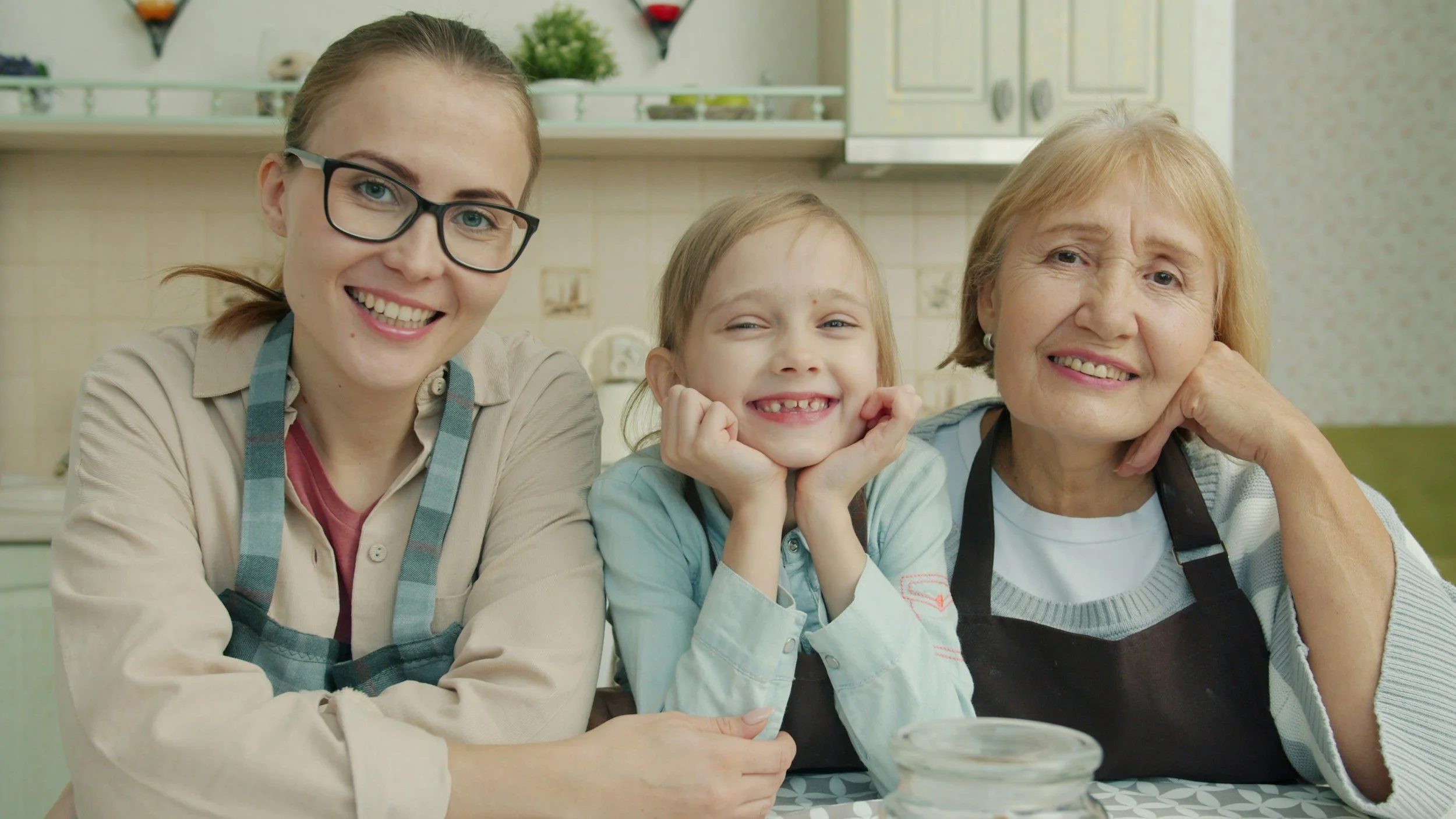 Three women and a girl smiling at the camera in a kitchen.