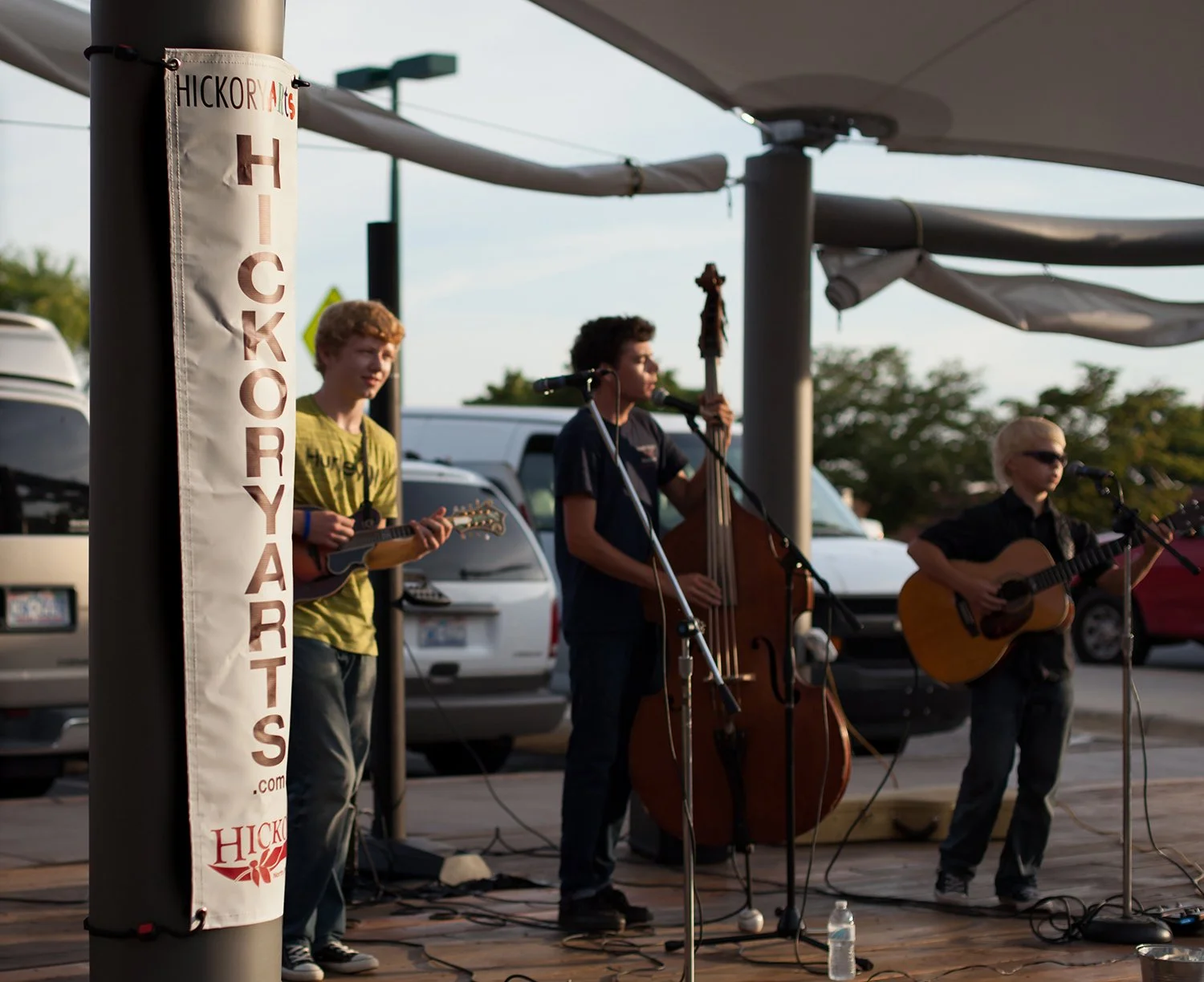 Hickory Arts student musicians performing live at an outdoor concert featuring mandolin, upright bass, and acoustic guitar players in North Carolina.