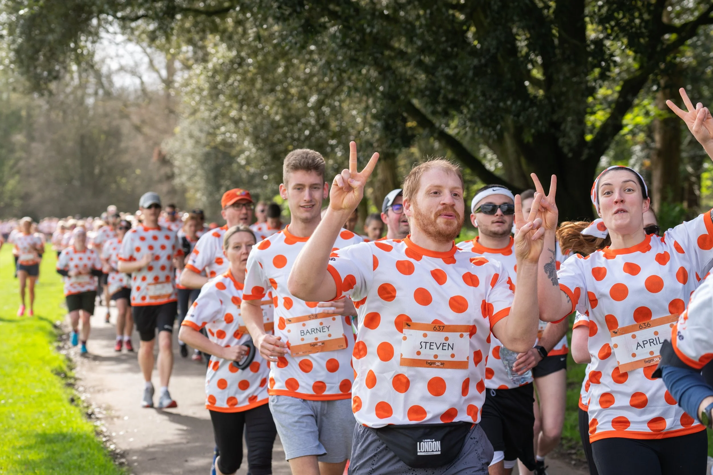 Hundreds of runners dressed in white shirts with bright orange dots for the Big Moose charity half marathon in Bute Park, Cardiff.