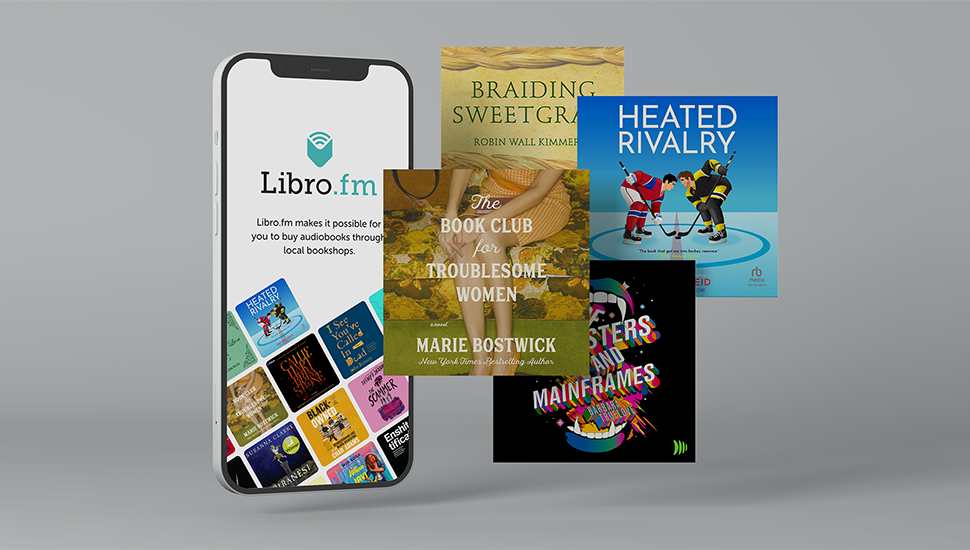 A smartphone displaying the Libro.fm app with audiobook covers, surrounded by physical book covers including "Braiding Sweetgrass," "Heated Rivalry," "The Book Club for Troublemaking Women," "Sisters and Mainframes," and "Black Black Black."