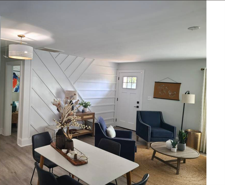 Living room with blue chairs, white wall with diagonal paneling, coffee table, and decorative items.