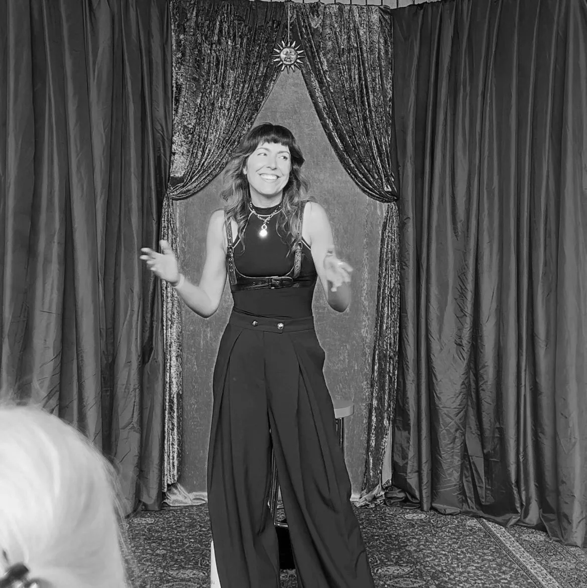 Becs Pearson copywriter standing between velvet stage curtains smiling